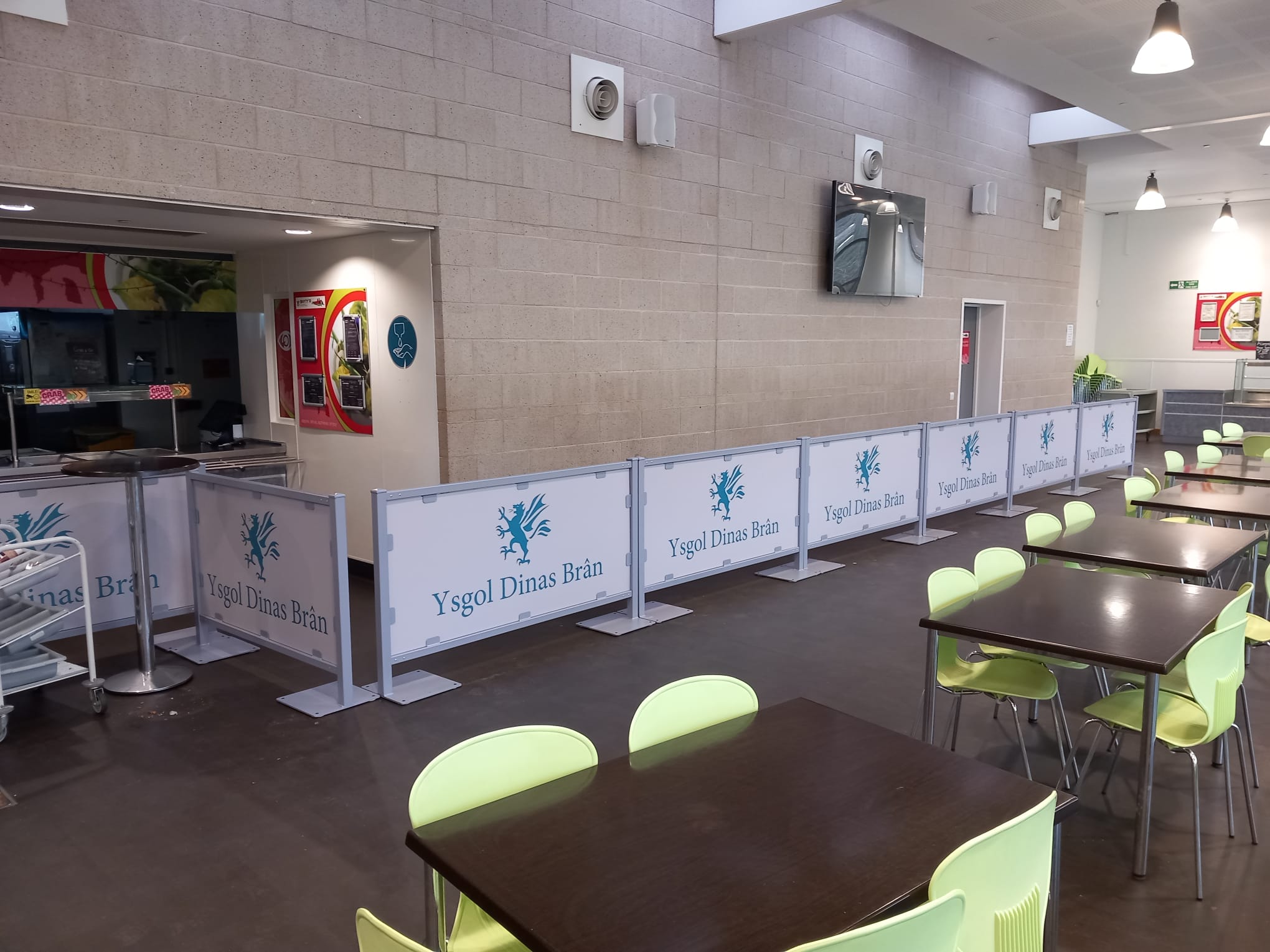 Branded metal queuing barriers installed in a school dining space