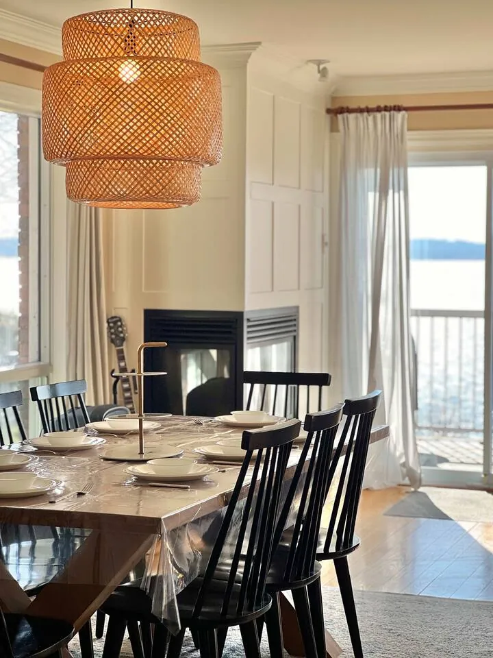 Dining table beside a double-sided gas fireplace at Bayside, with water views