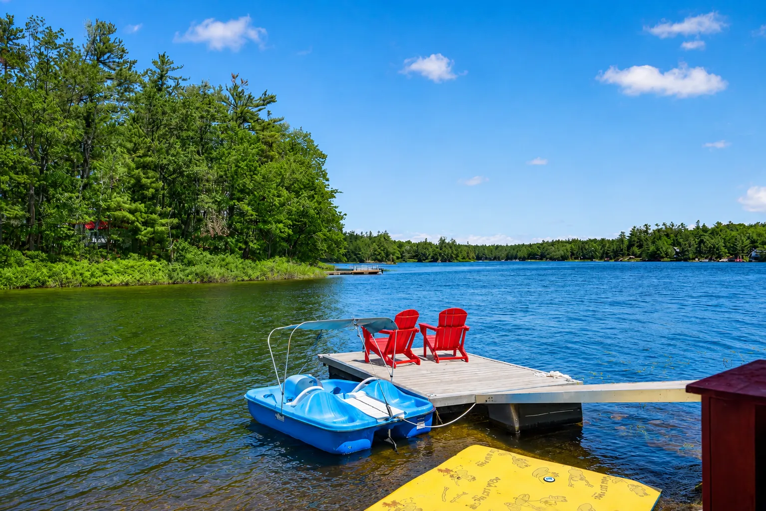 Dock at Good Times with a paddle boat and red chairs on a blue summer day