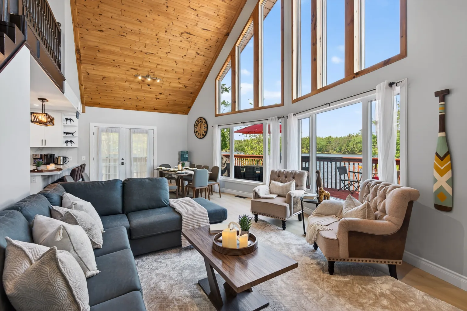 Vaulted great room at Good Times with a wall of floor-to-ceiling windows and grey sectional sofas