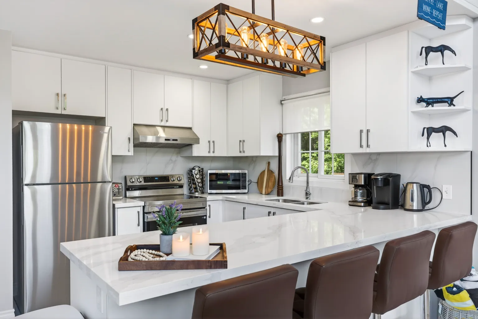White kitchen at Good Times with a long island and bar stools under a pendant light