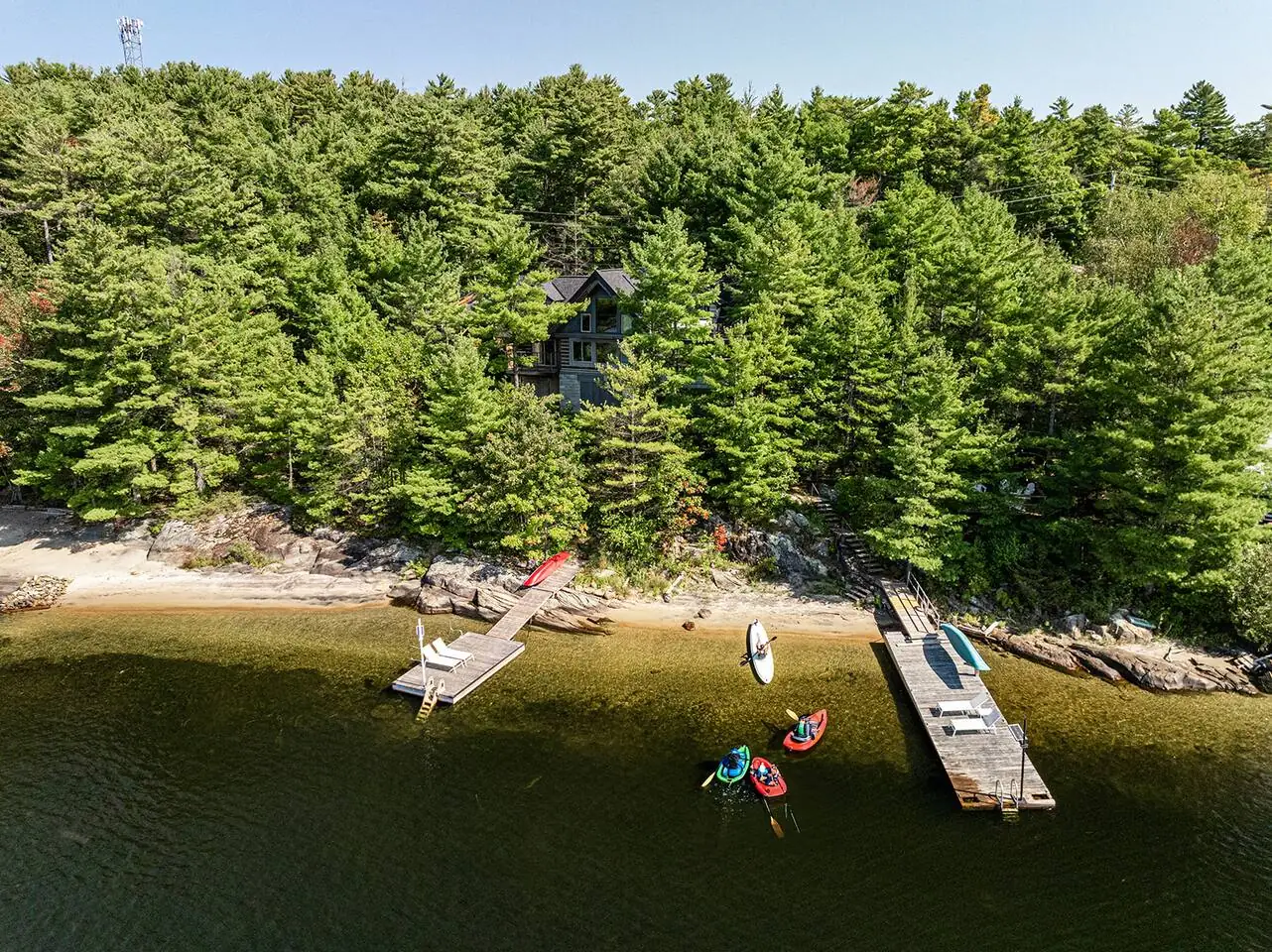 Aerial view of the Hemlock Hideaway shoreline in summer with its dock and a canoe on the water