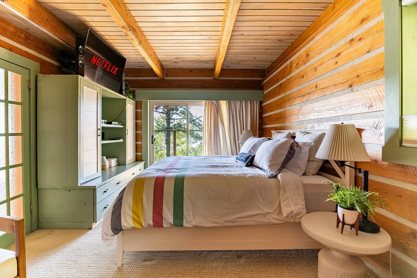 Bedroom at Hemlock Hideaway with log walls and a striped wool blanket on the bed