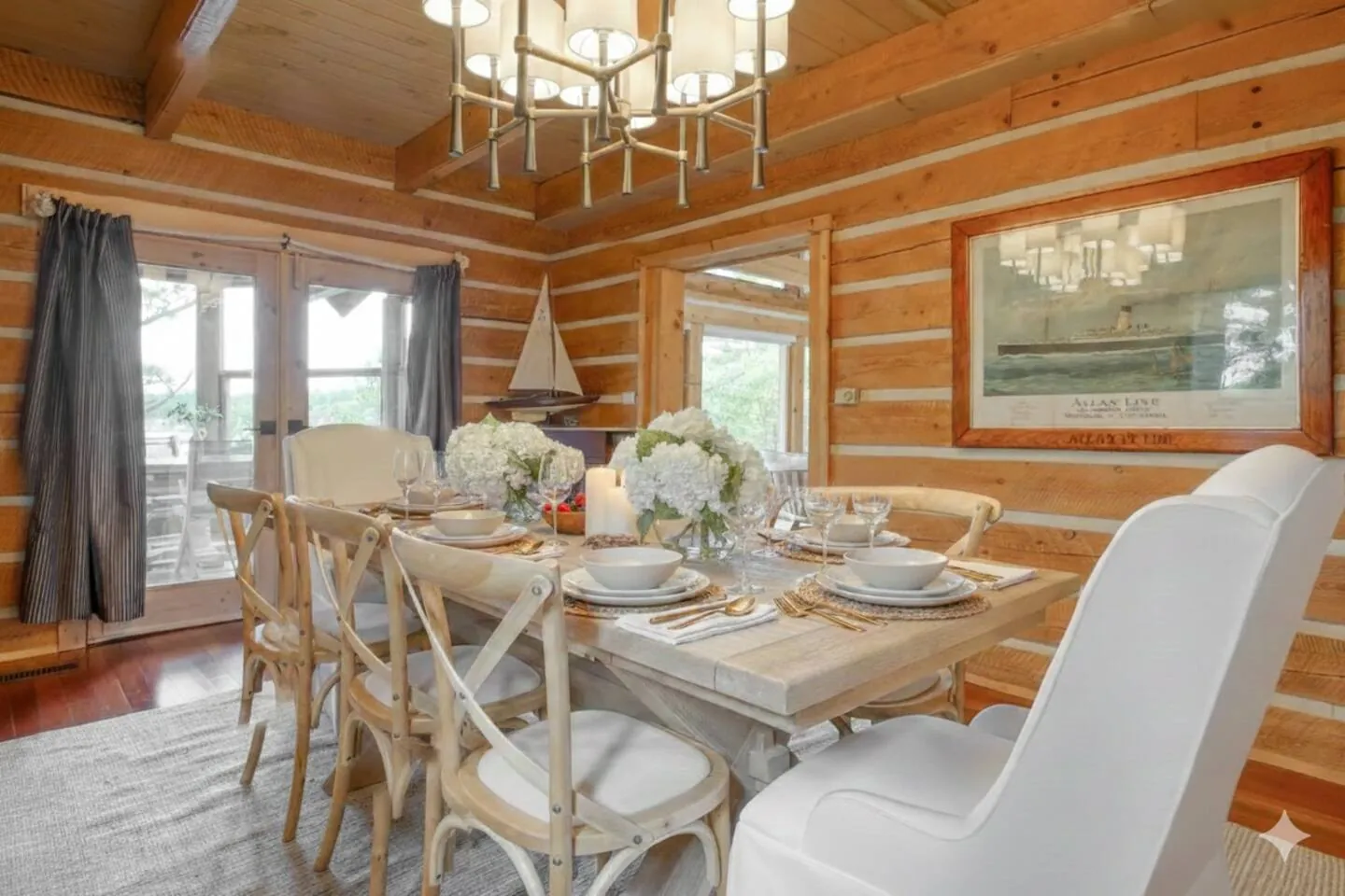 Dining room at Hemlock Hideaway with a chandelier, white chairs and log walls