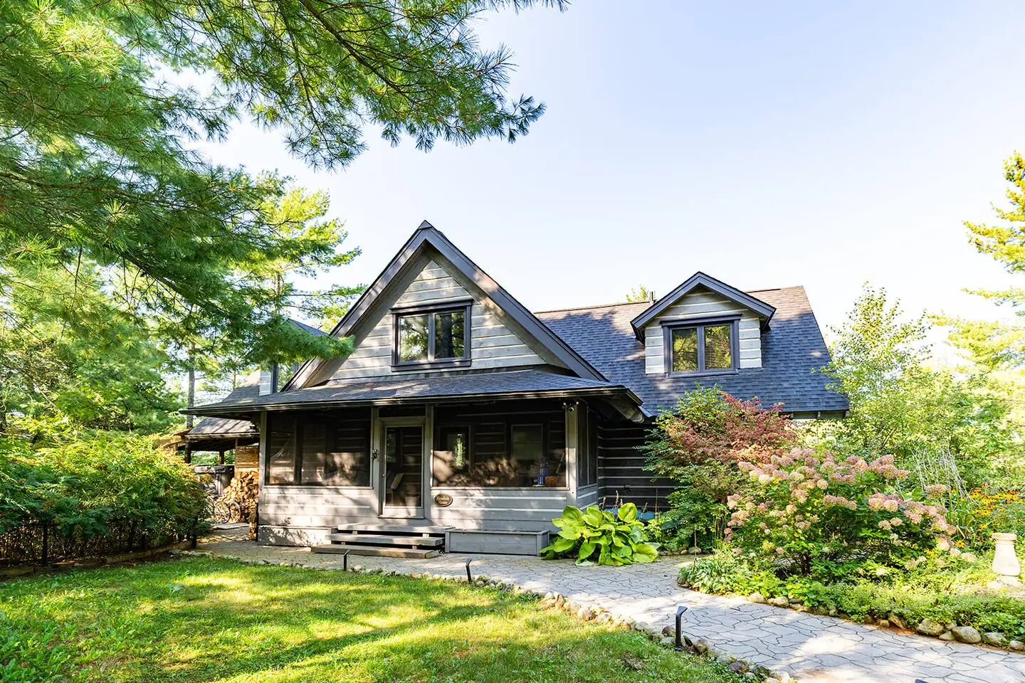 Exterior of the Hemlock Hideaway log home with dormers, a covered porch and a green lawn