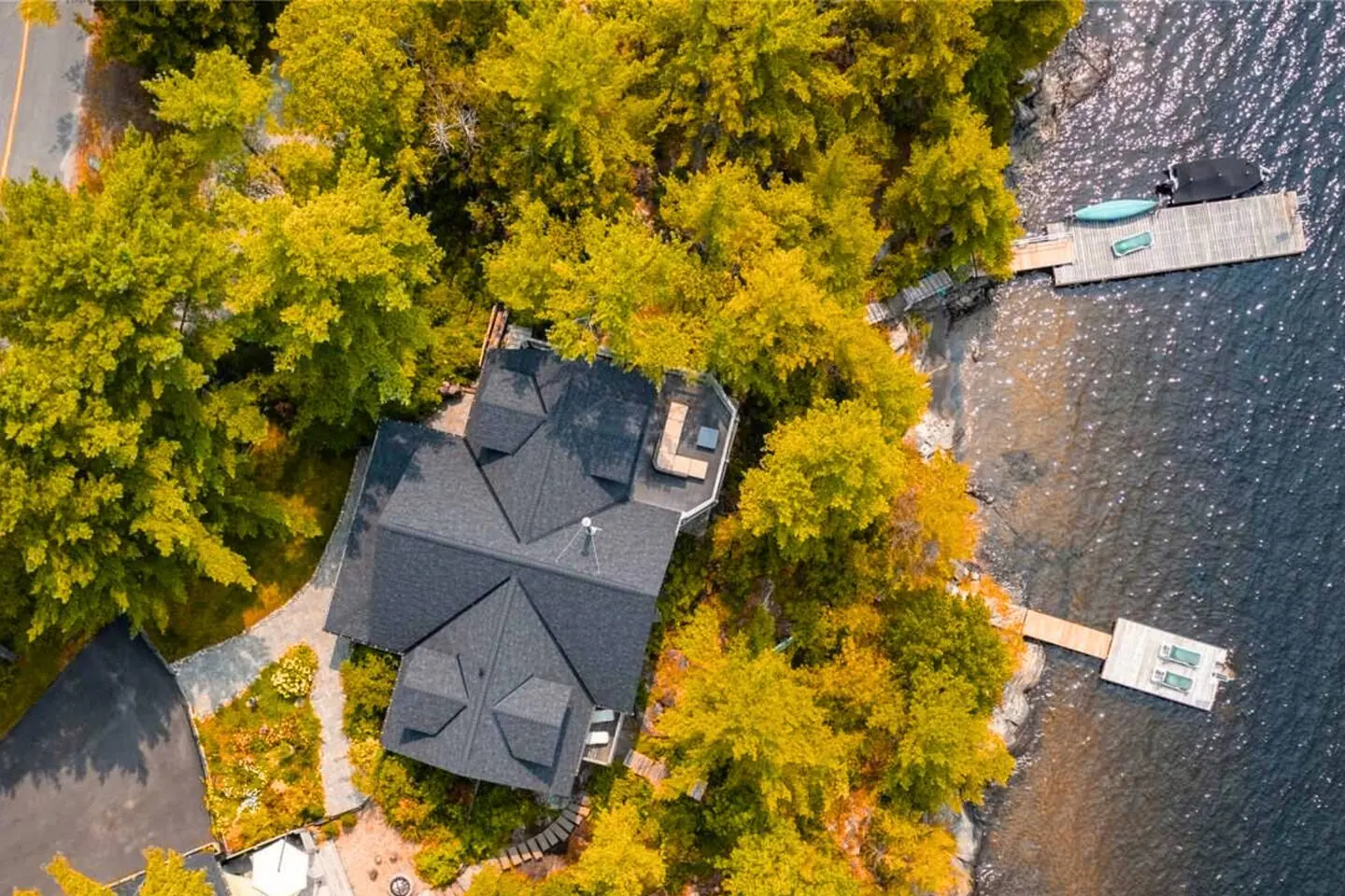 Aerial view of Hemlock Hideaway in Parry Sound in autumn, with red and gold trees along the rocky shore and the dock