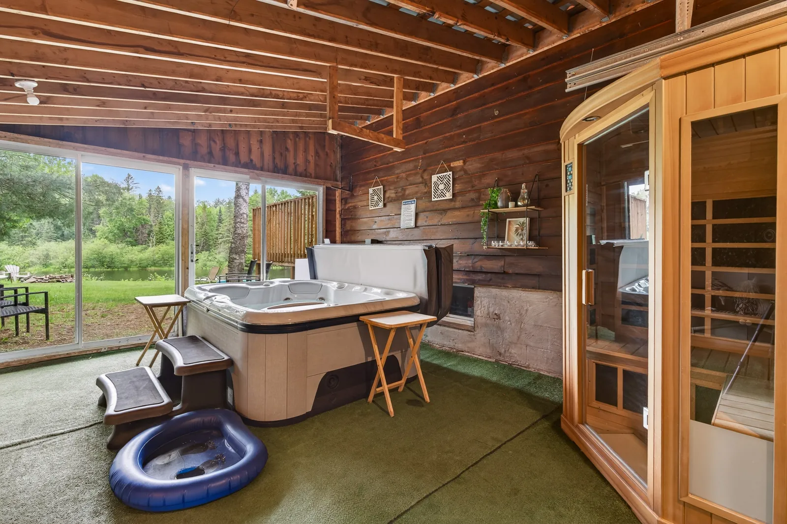 The Mara wellness room with a hot tub and a glass-fronted sauna beside sliding doors to the woods