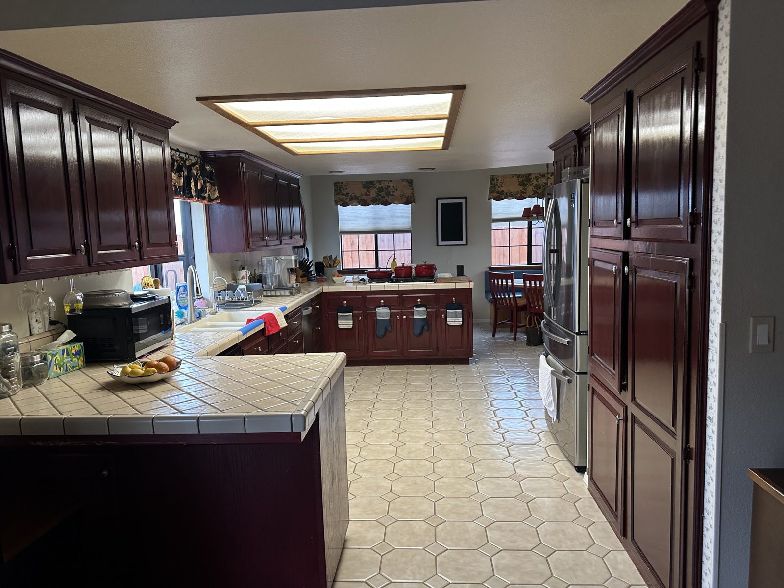 Kitchen before remodel with dark cherry cabinets, white tile countertops and octagon tile floor