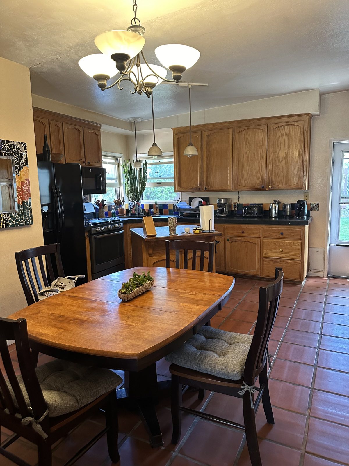 Kitchen and dining area before remodel with oak cabinets, terracotta tile floor and dining table