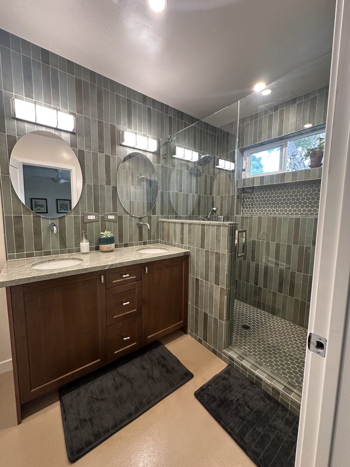 Full view of finished bathroom with double vanity and glass walk-in shower