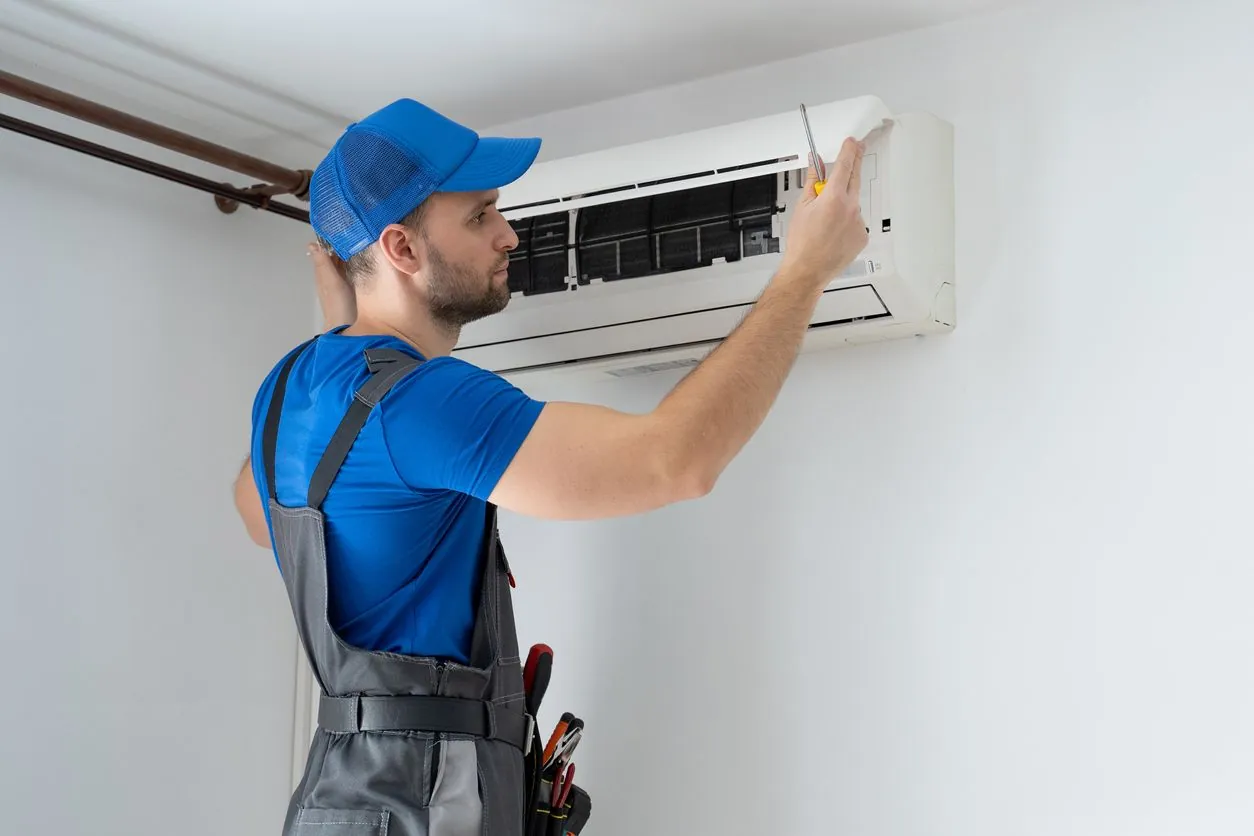 HVAC technician servicing a wall-mounted air conditioning unit