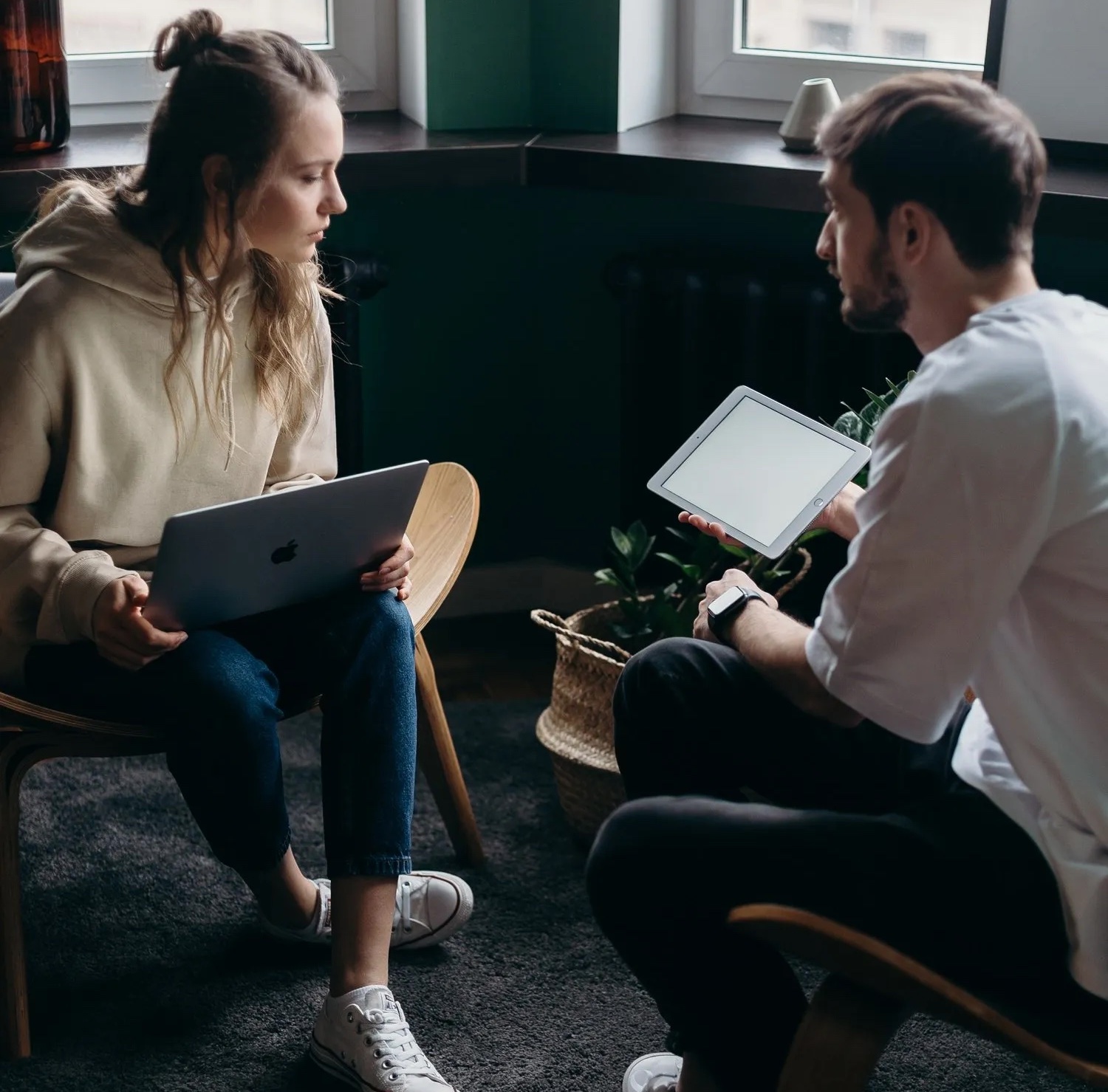 A man and woman seated in chairs, focused on their laptops, discussing homeownership options in Washington.