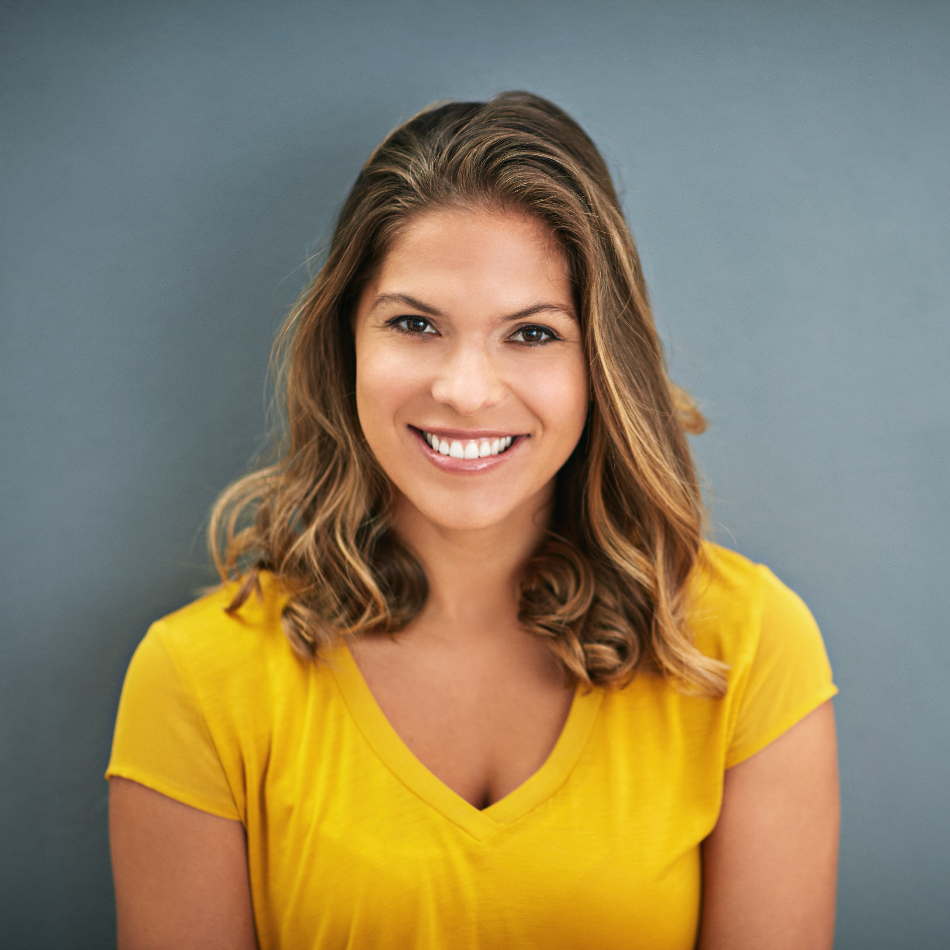 Smiling woman in a yellow shirt, showcasing confidence and vitality, representing rejuvenation and wellness at My Ageless Lounge.