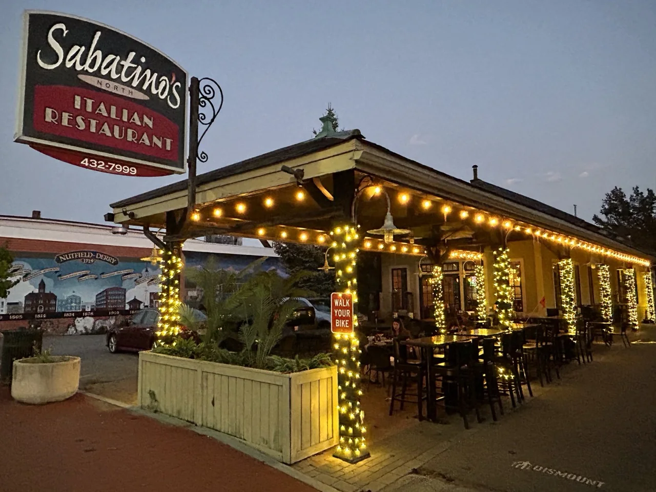 Completed Peak Lights warm-white roofline and patio-column lighting at Sabatino's North in Derry, New Hampshire
