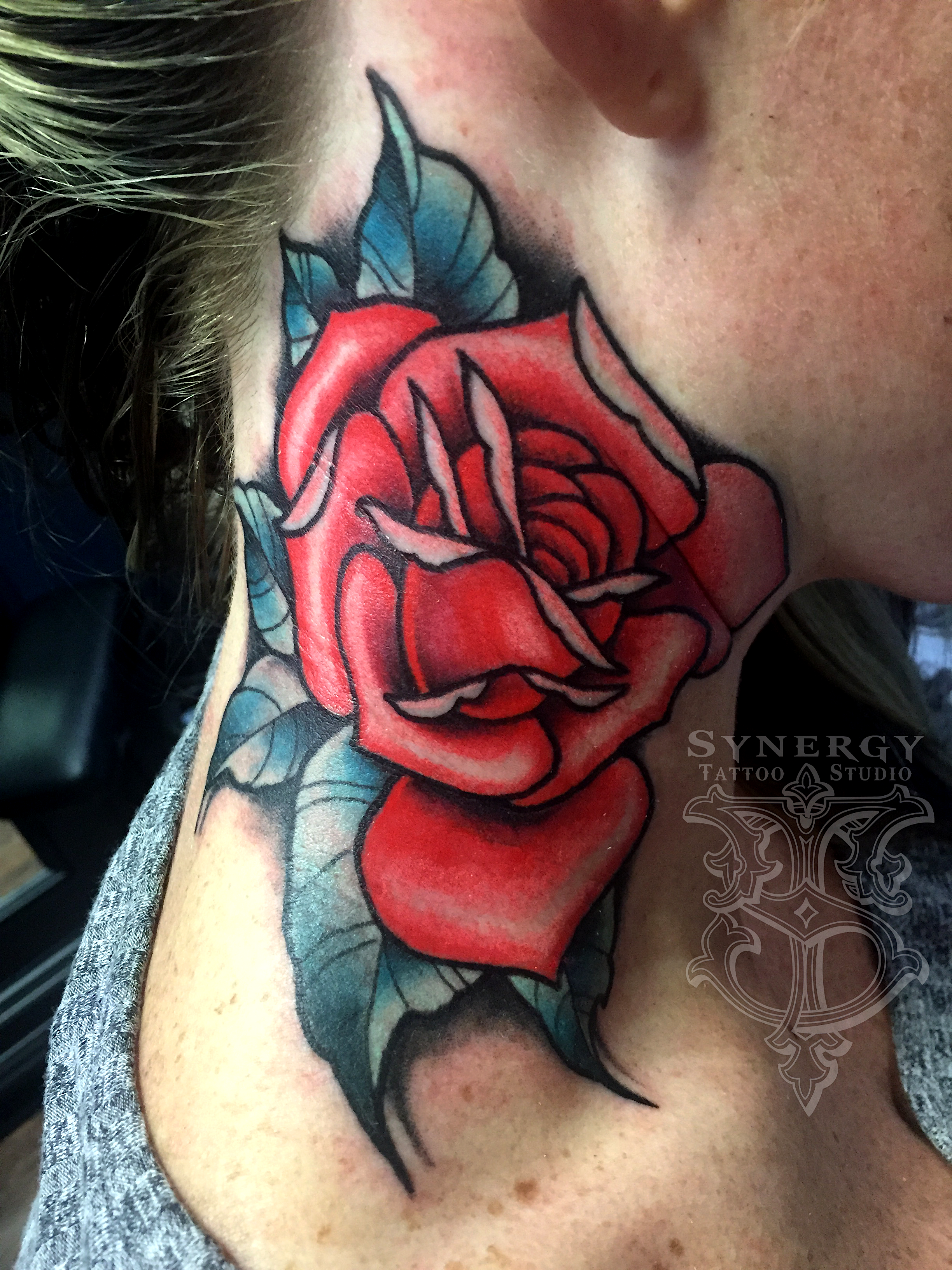 Red rose tattoo with blue leaves on the side of the neck