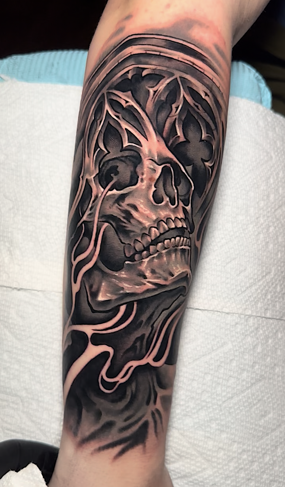 Black and grey skeletal face tattoo with dark ornamental flames