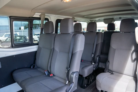Rows of grey passenger seats with seatbelts inside the minibus