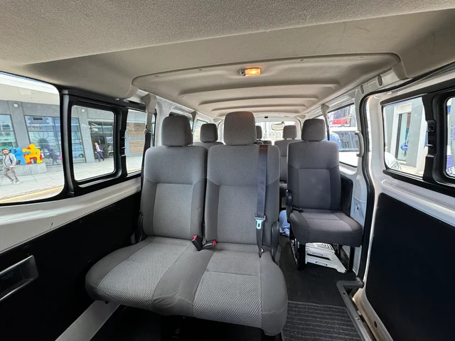 The minibus cabin from the side door, showing bench seats and tinted windows