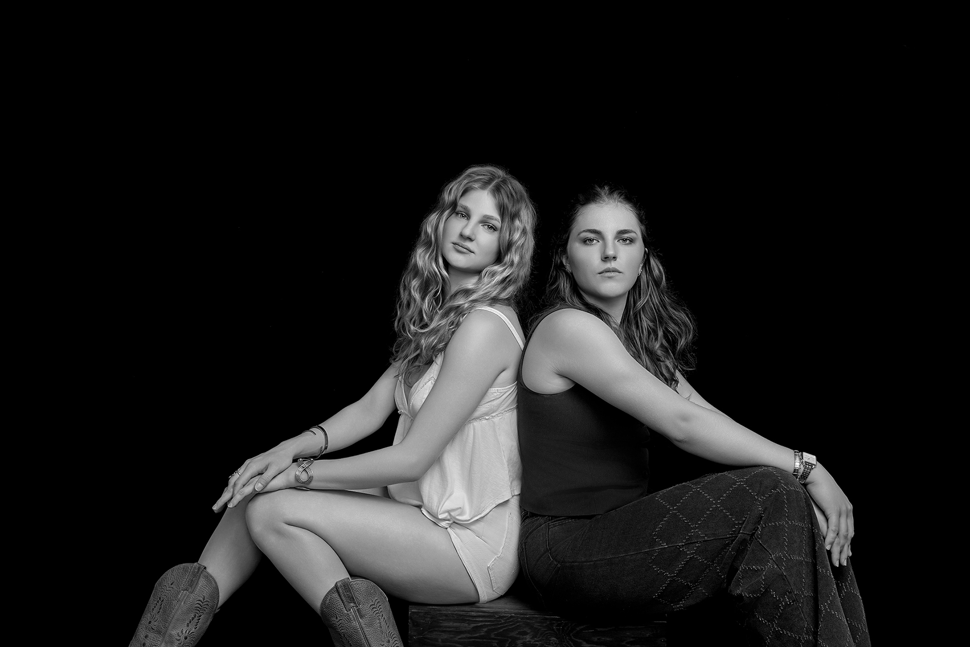 Black and white studio portrait of two women seated closely together, photographed by Janice Smith Photography. Black and white studio portrait of two women seated closely together, photographed by Janice Smith Photography.