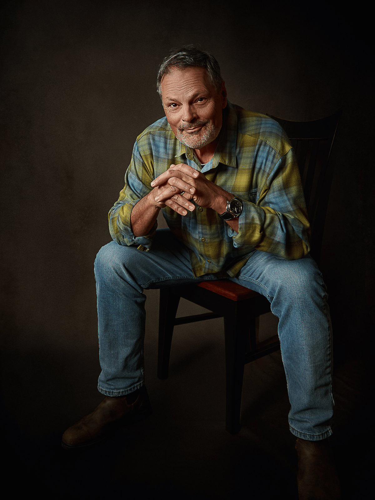 Studio portrait of a seated man in a plaid shirt, photographed by Janice Smith Photography.