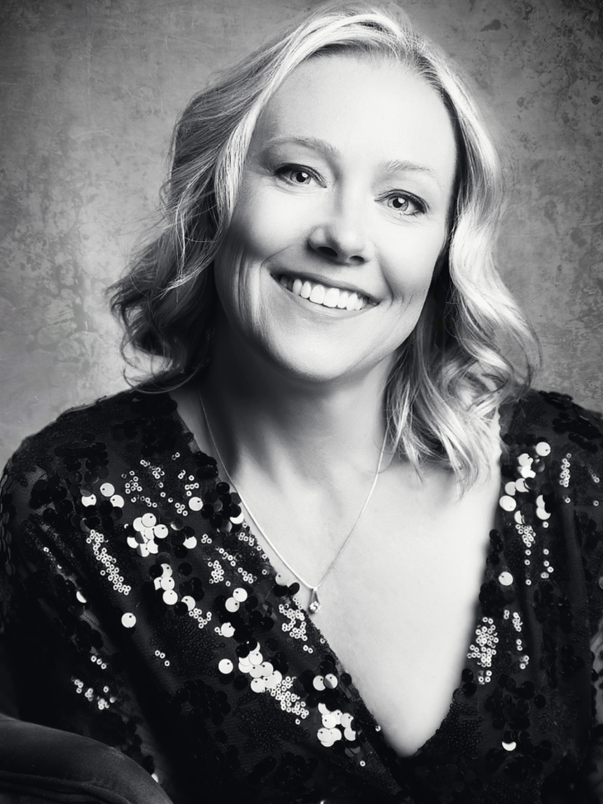 Black and white studio portrait of a smiling woman looking at the camera, photographed by Janice Smith Photography.