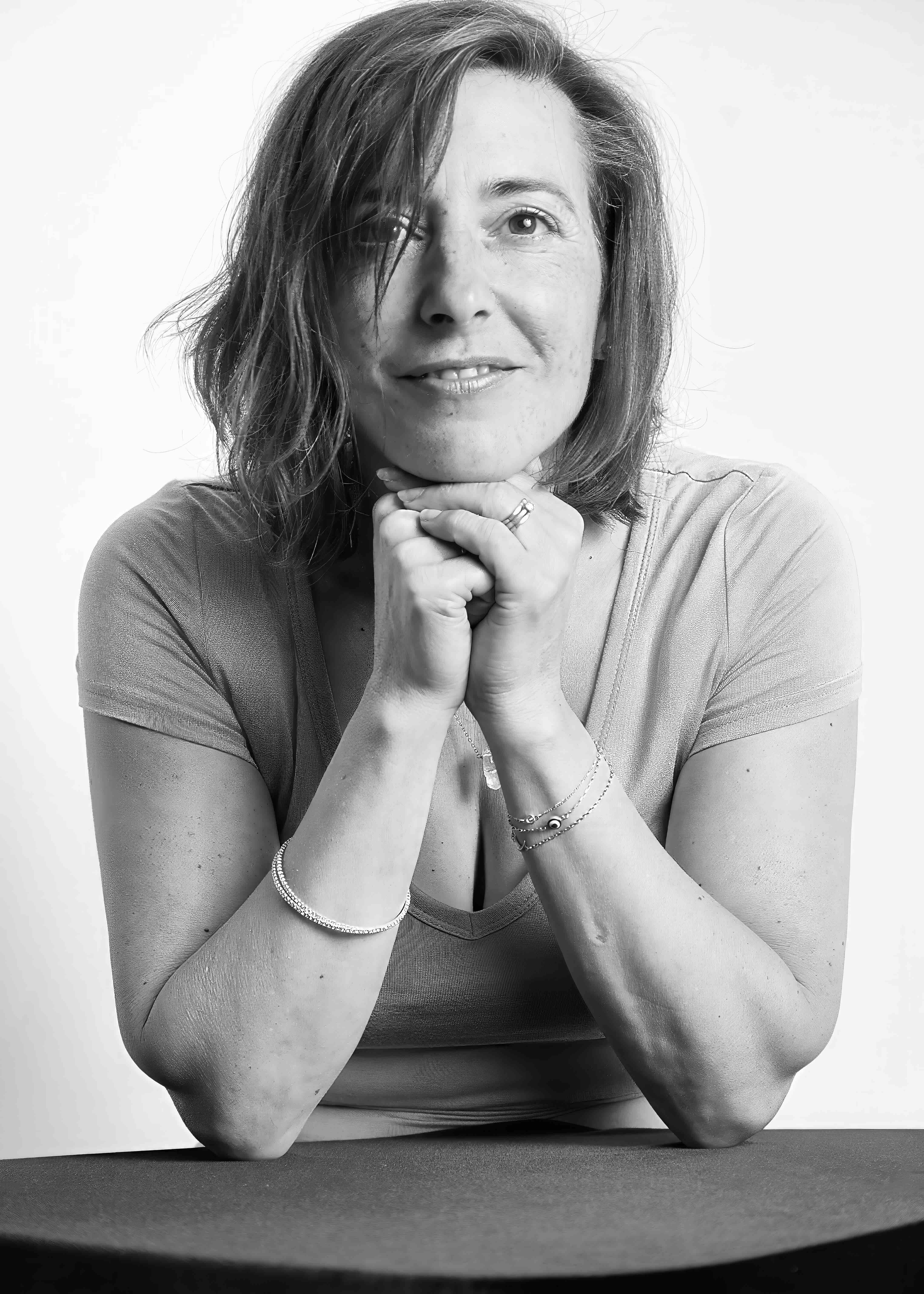 Black and white studio portrait of a woman resting her chin on her hands, photographed by Janice Smith Photography. Black and white studio portrait of a woman resting her chin on her hands, photographed by Janice Smith Photography.