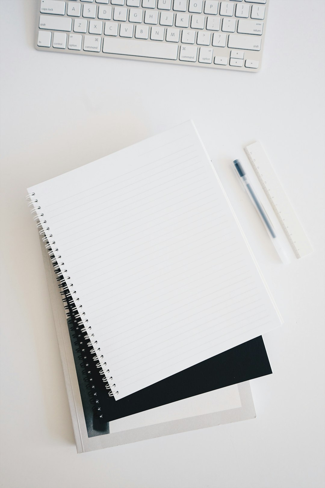 Close-up of three white hardcover books stacked on a white surface against a plain white background with open space at left.