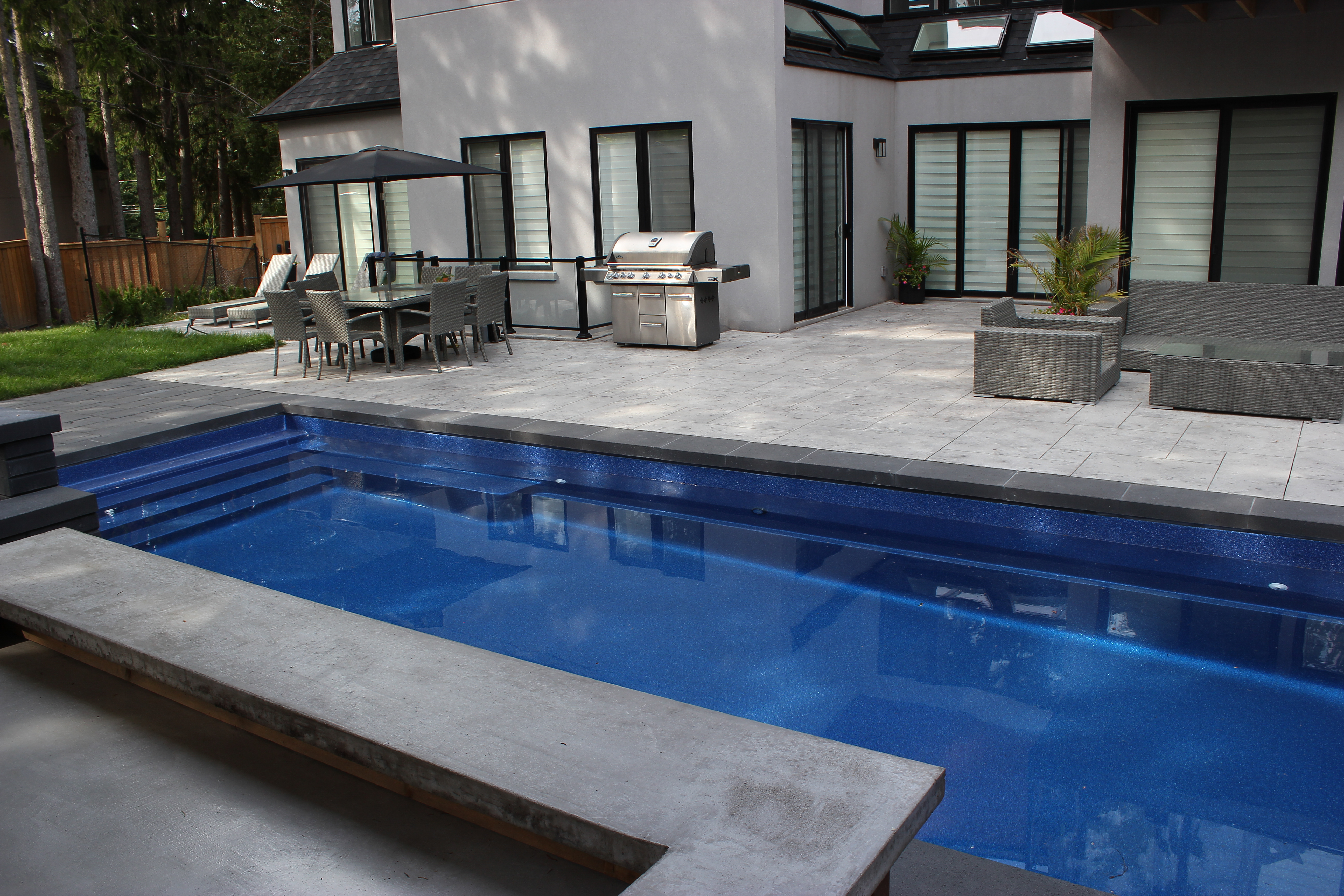 Aerial view of a modern backyard with swimming pool, patio, and landscaped outdoor living space.