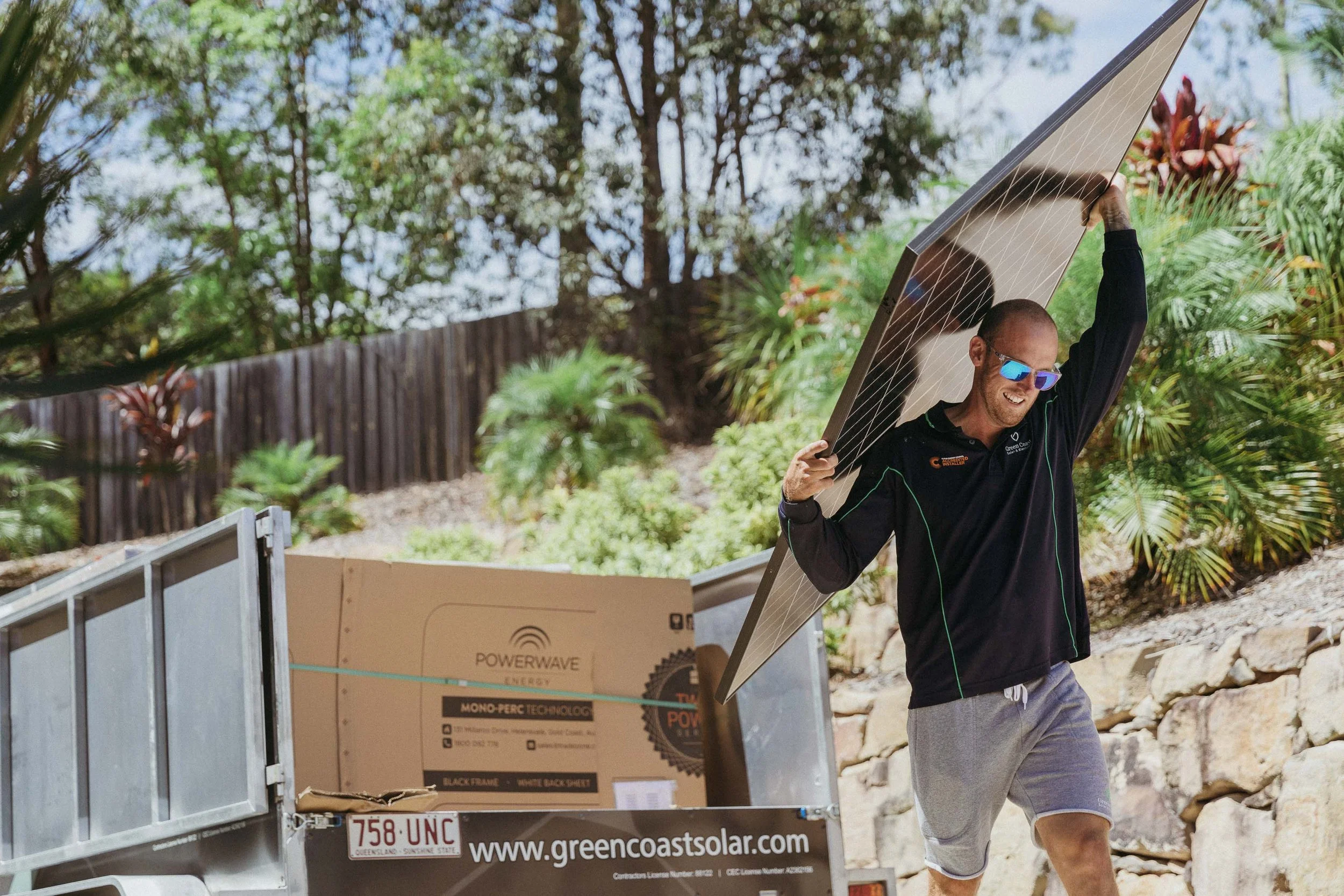 Green Coast team carrying a solar panel during a home install