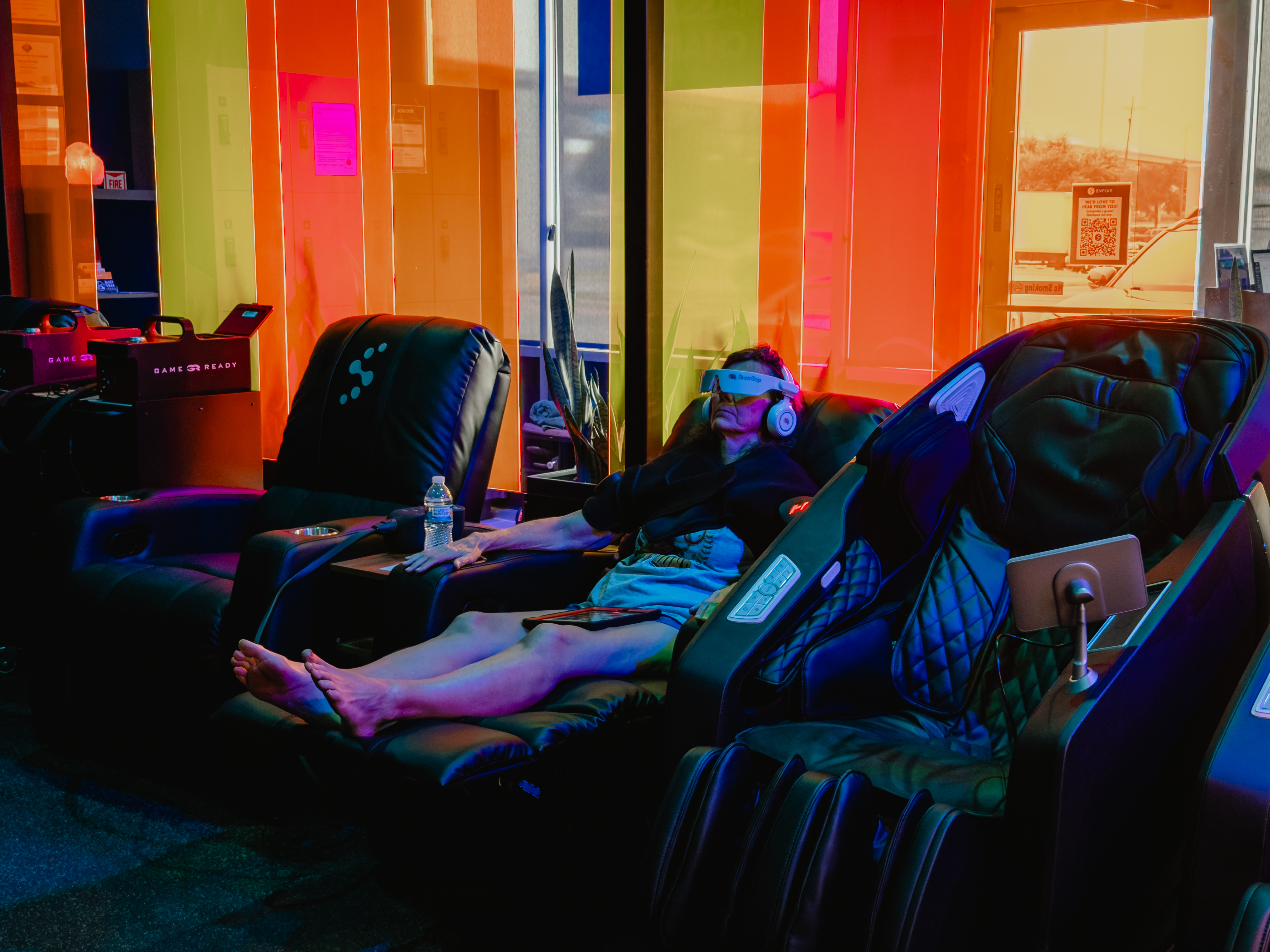 Woman using BrainTap headset in massage chair by window at Evolve Social Wellness Space