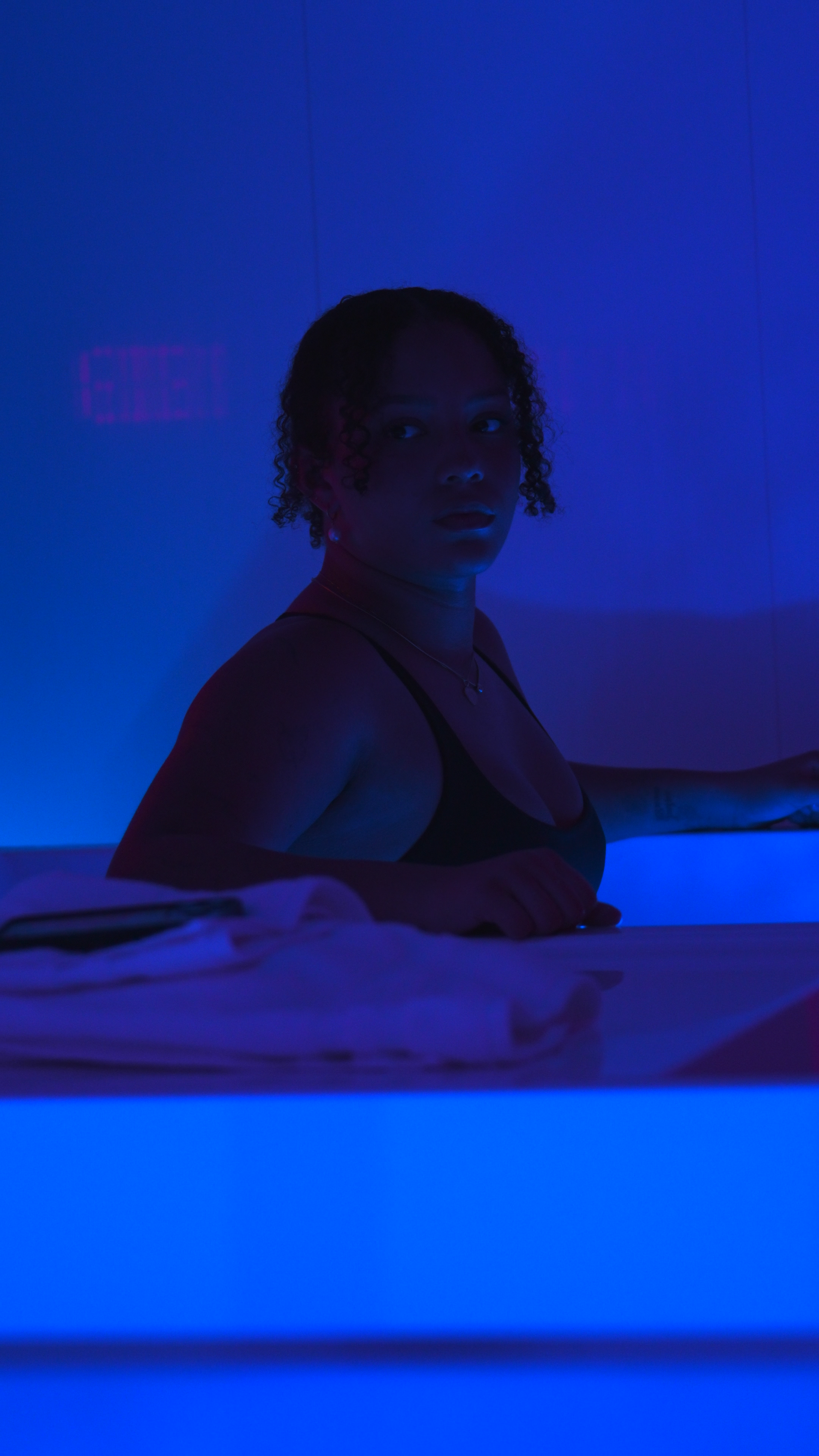 Portrait of woman in cold plunge with blue lighting at Evolve