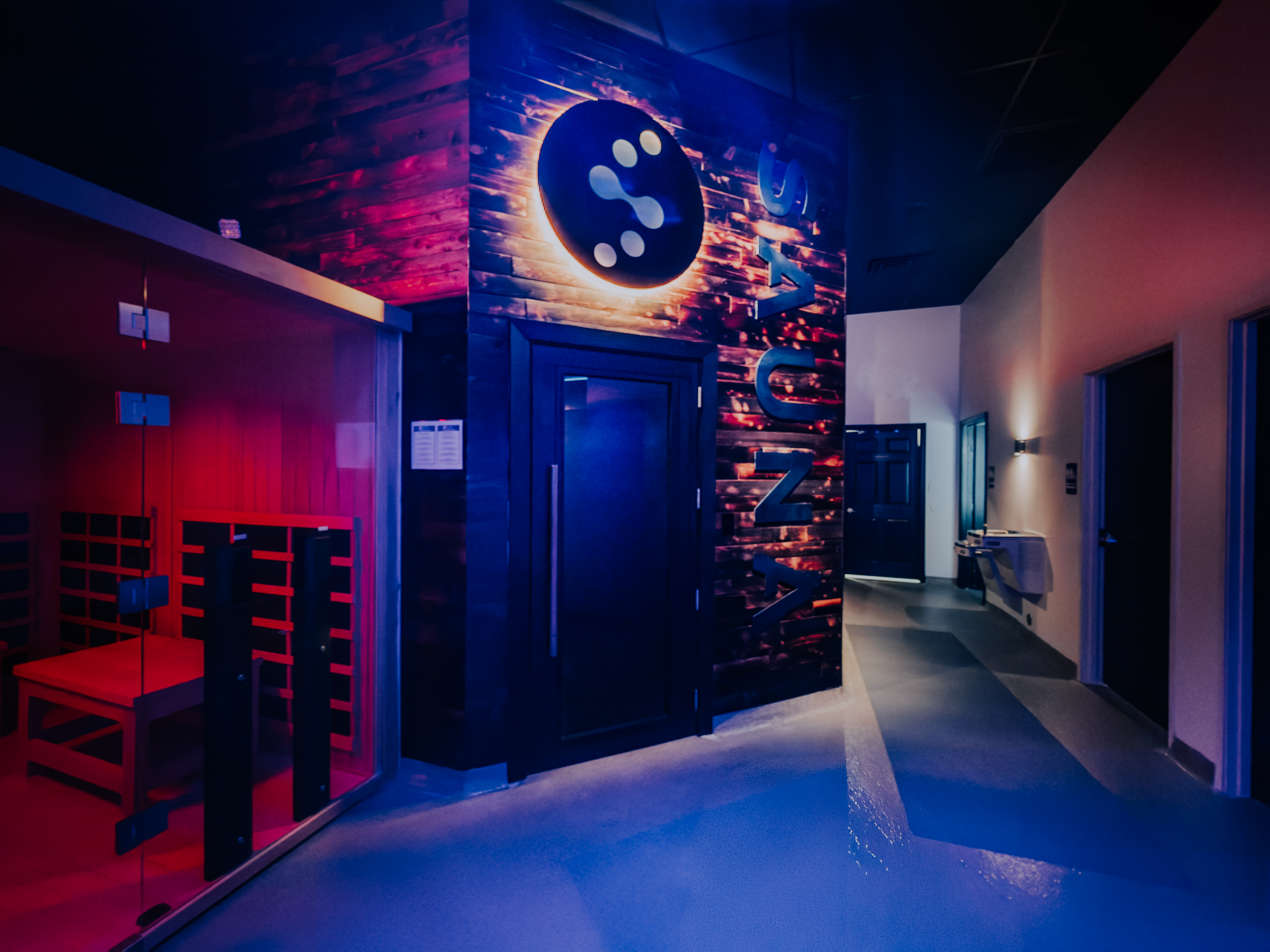 Backlit Evolve logo on sauna hallway door with blue and red ambient lighting