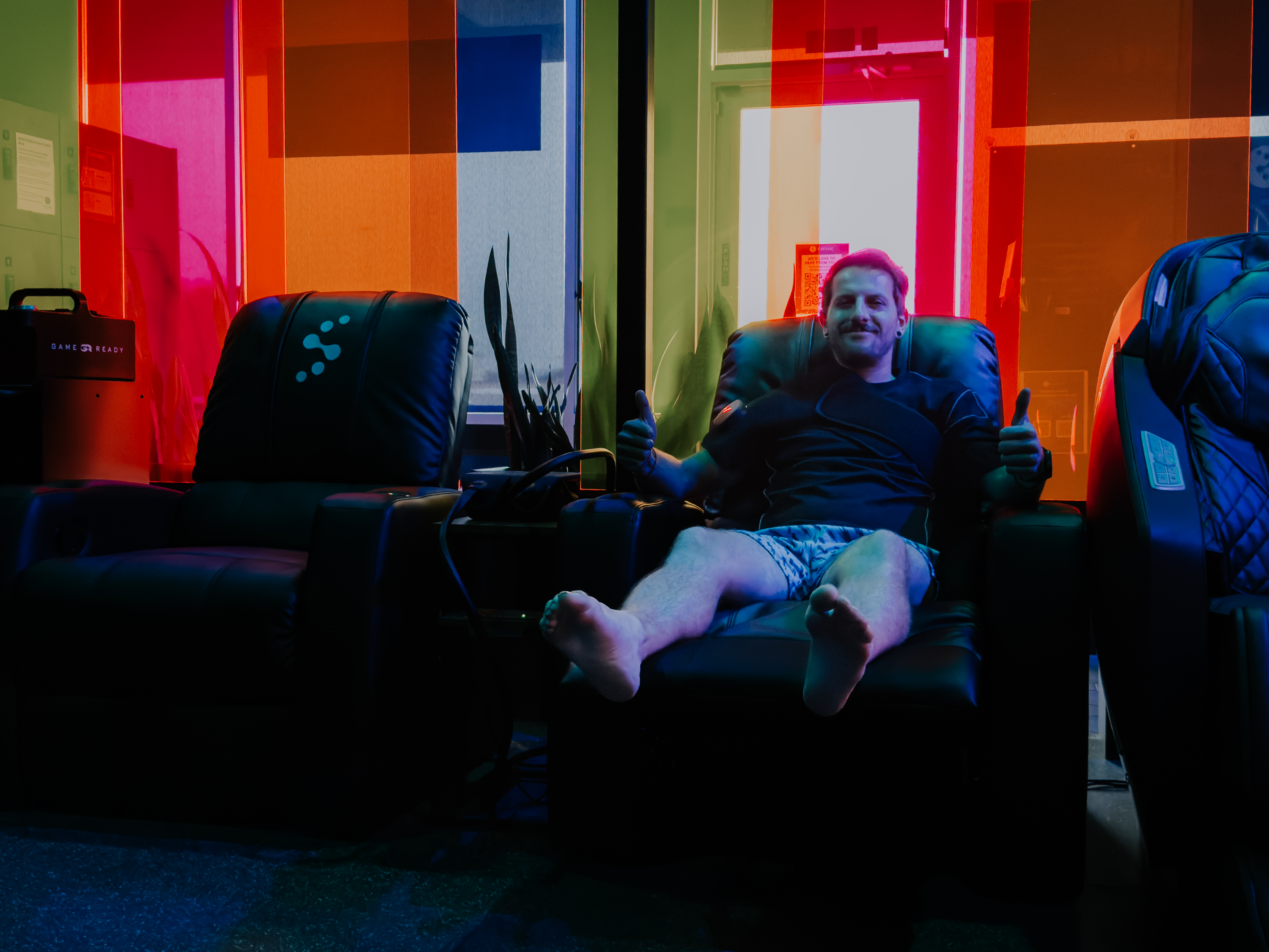 Happy member giving thumbs up while relaxing in massage chair at Evolve