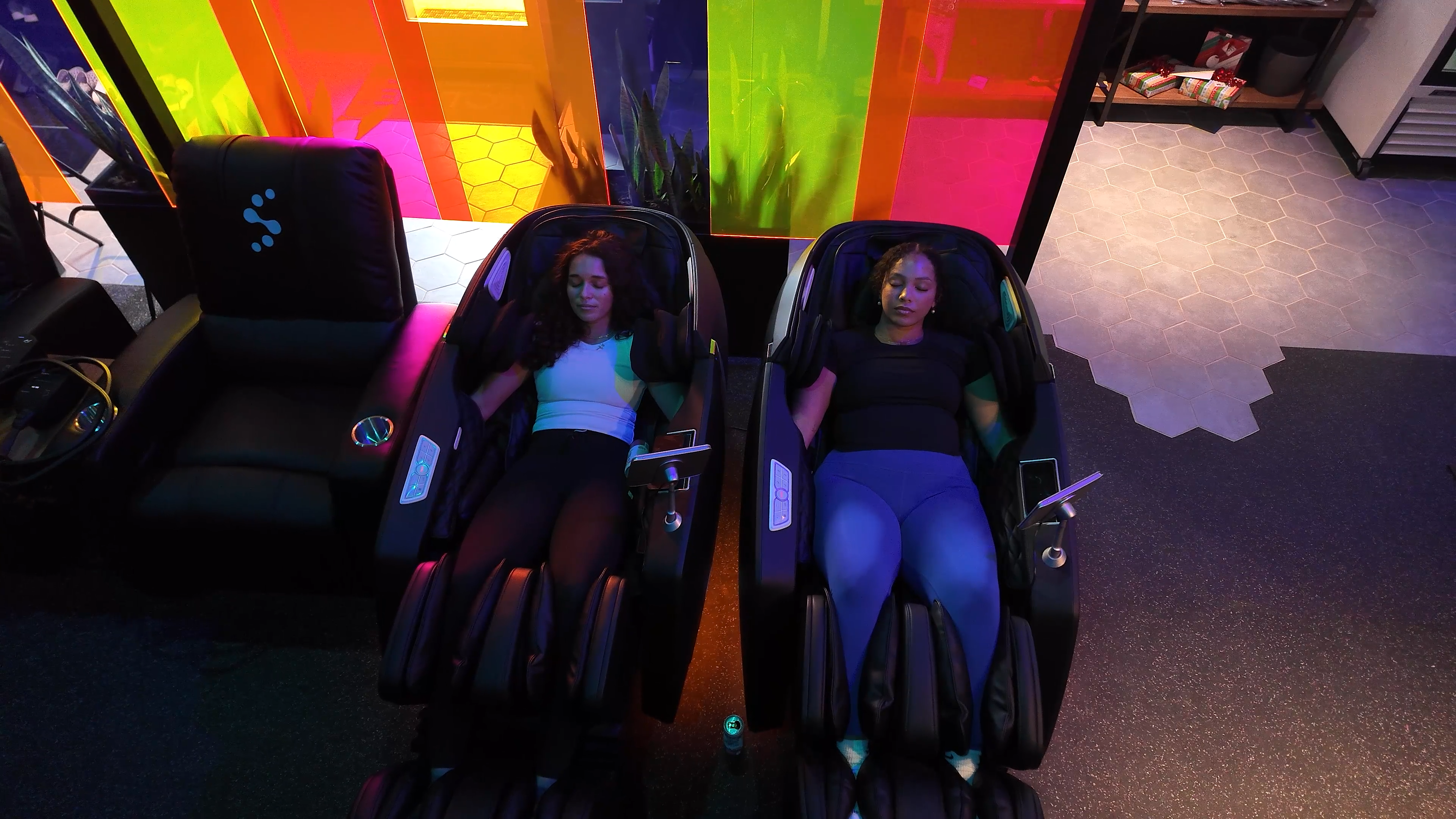 Two women relaxing in massage chairs at Evolve Social Wellness Space BrainTap lounge