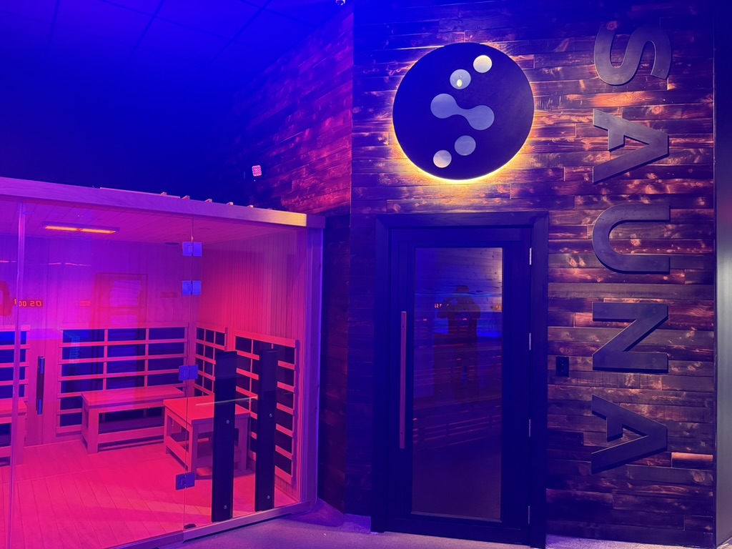 Wide view of Norwegian sauna entrance with illuminated Evolve logo at Evolve Social Wellness Space Round Rock