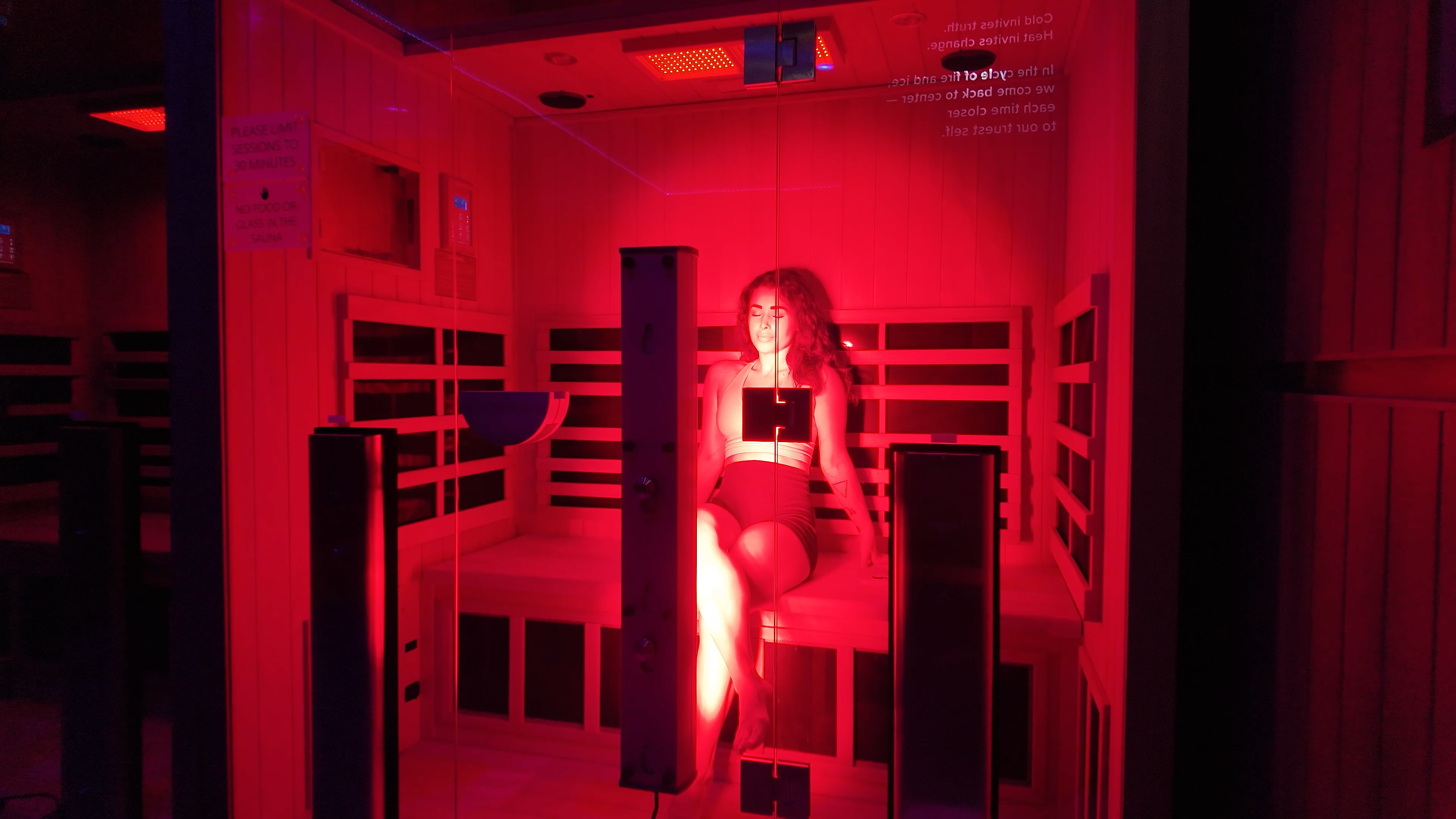 Woman inside red light therapy cabin with warm red glow at Evolve