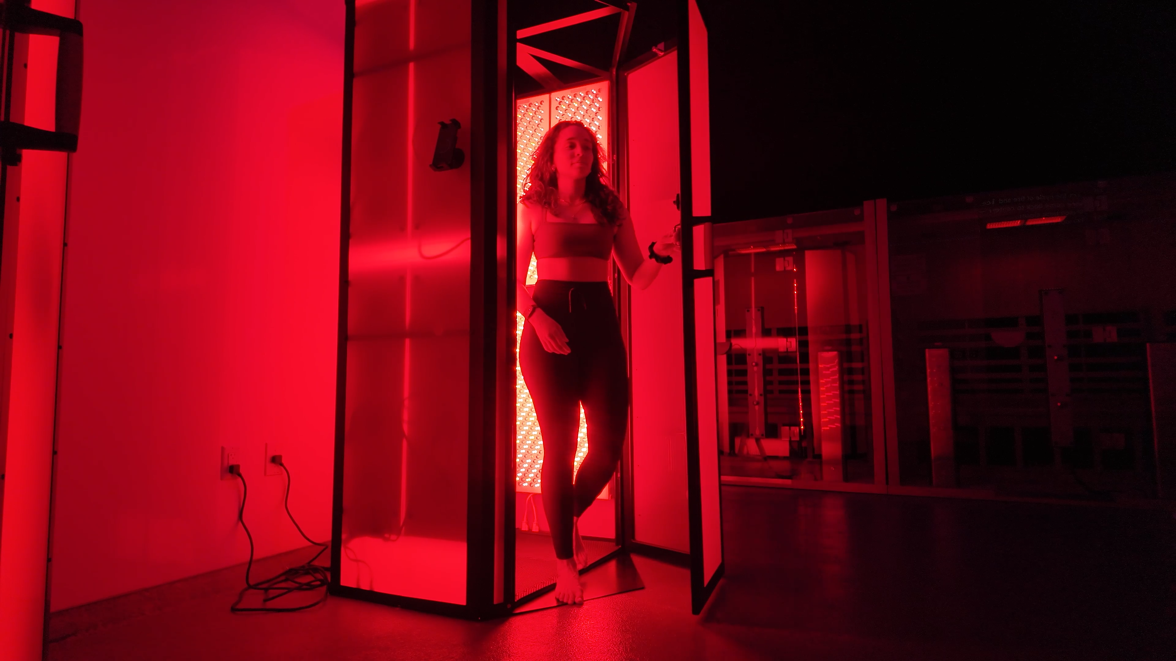Woman in red light therapy booth at Evolve