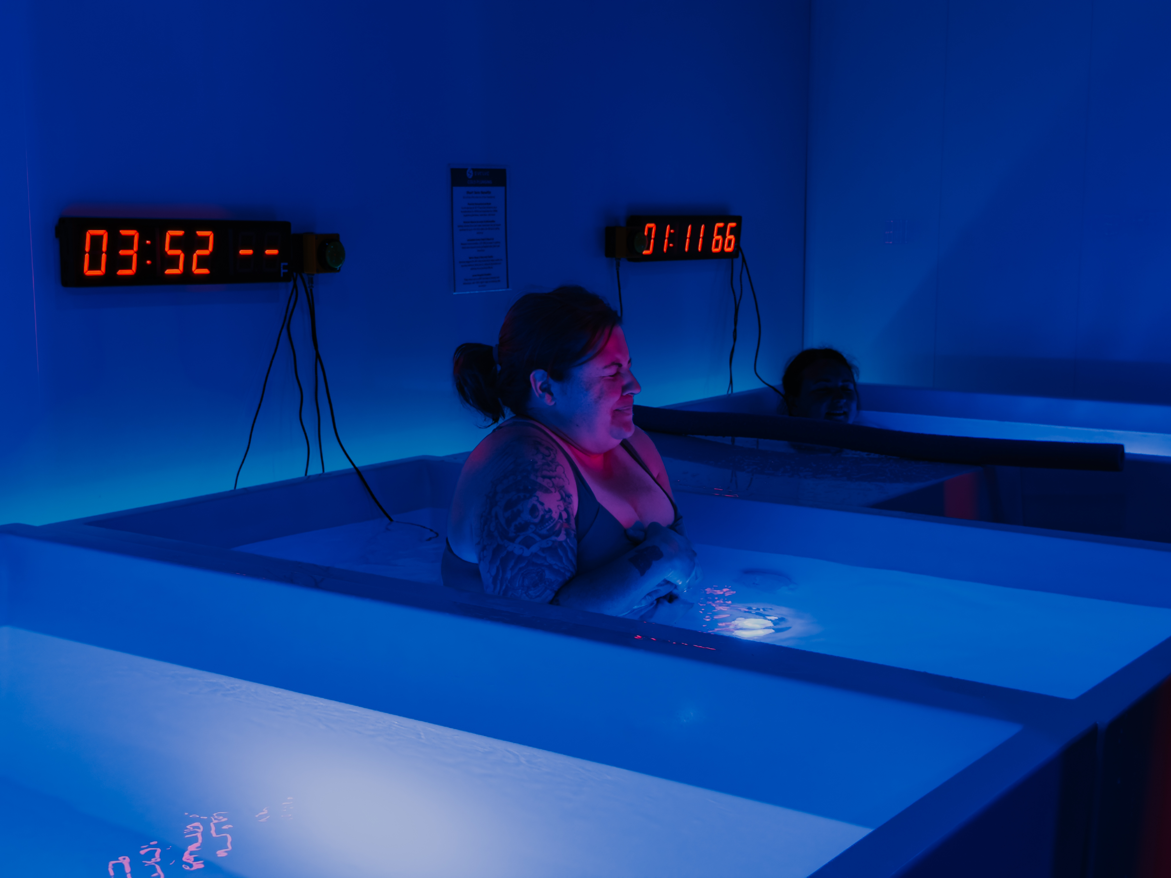 Woman with tattoos smiling while submerged in cold plunge at Evolve