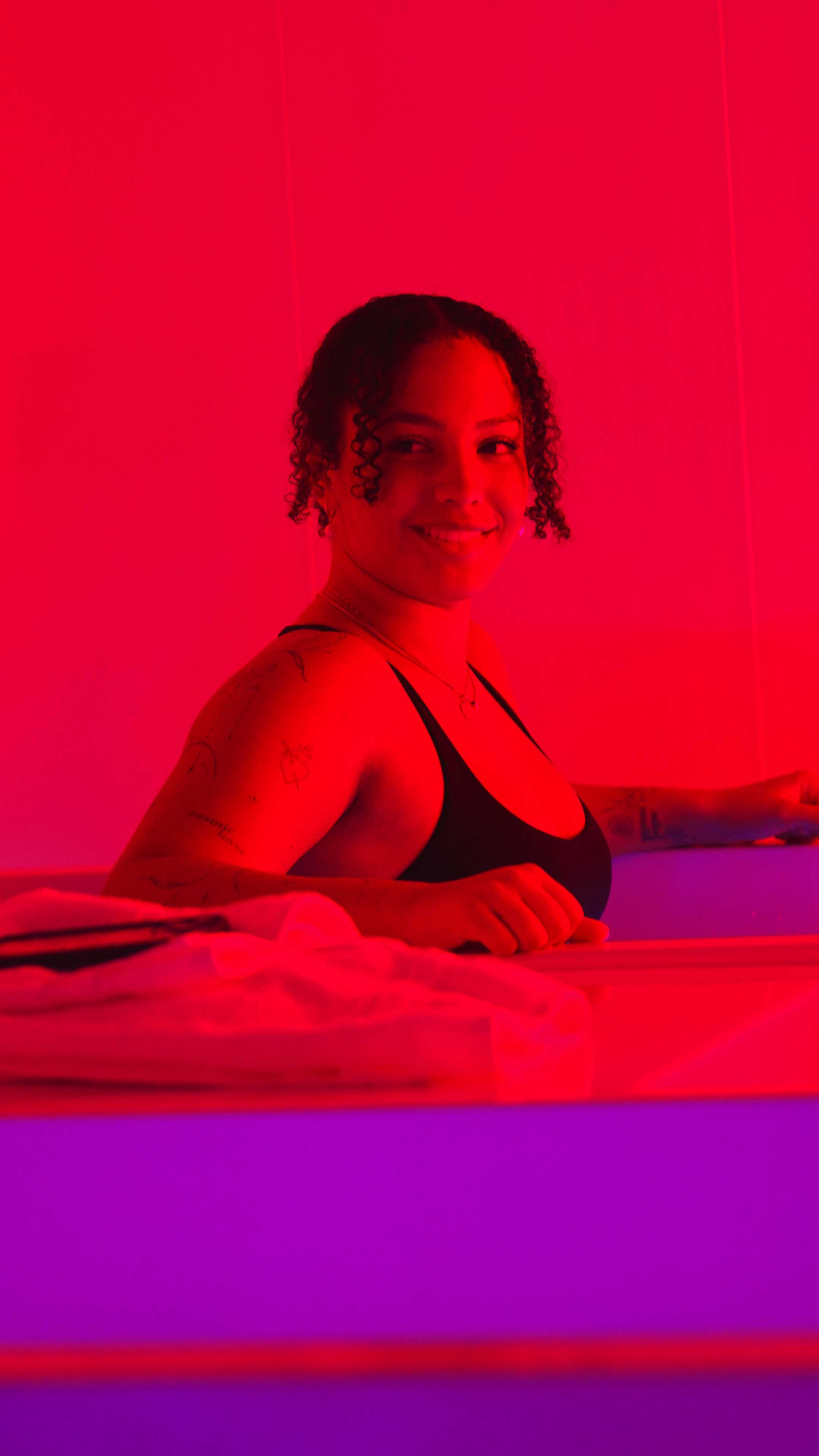 Woman in cold plunge with red ambient glow at Evolve