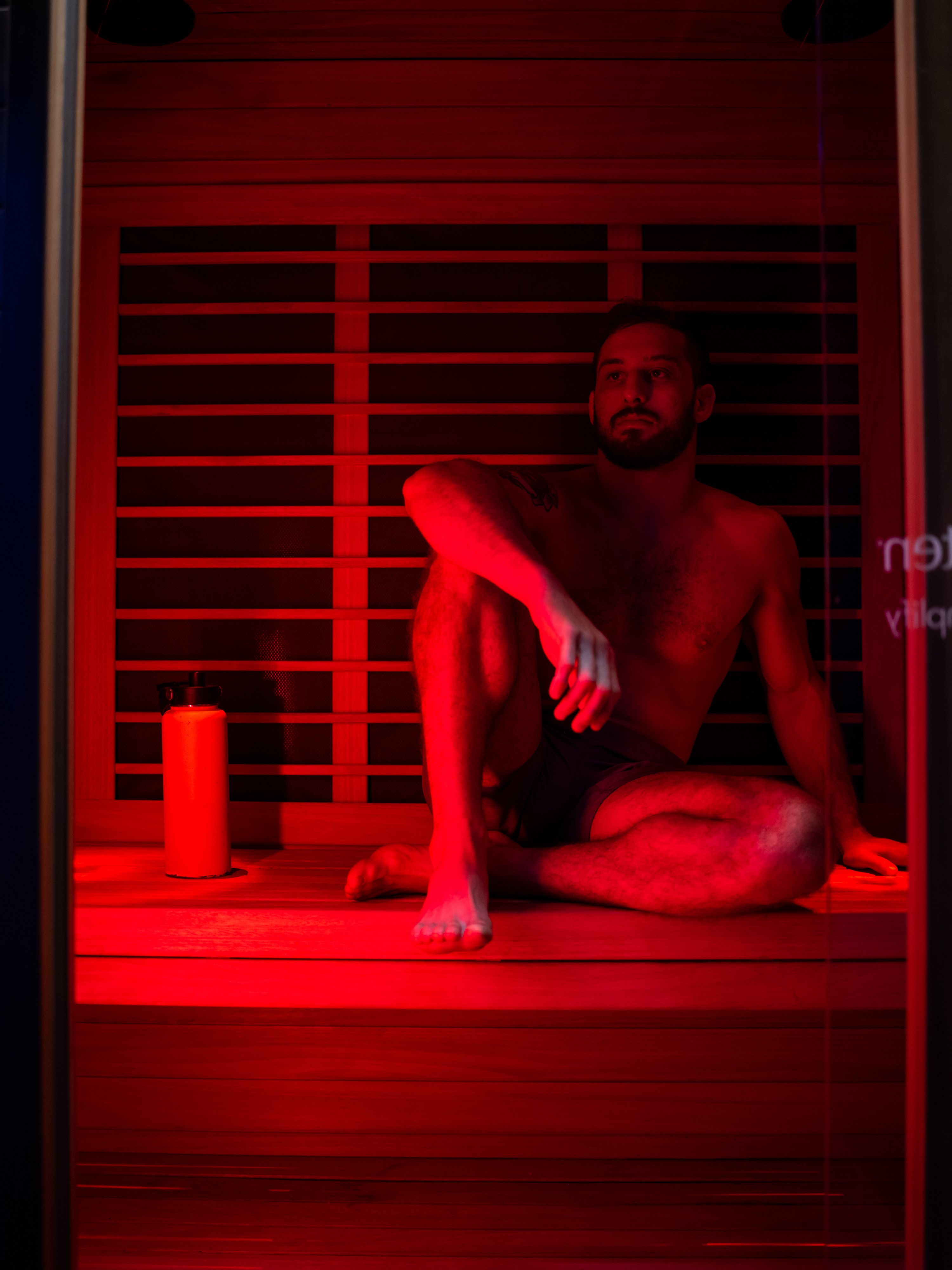 Man seated in infrared sauna with red ambient glow