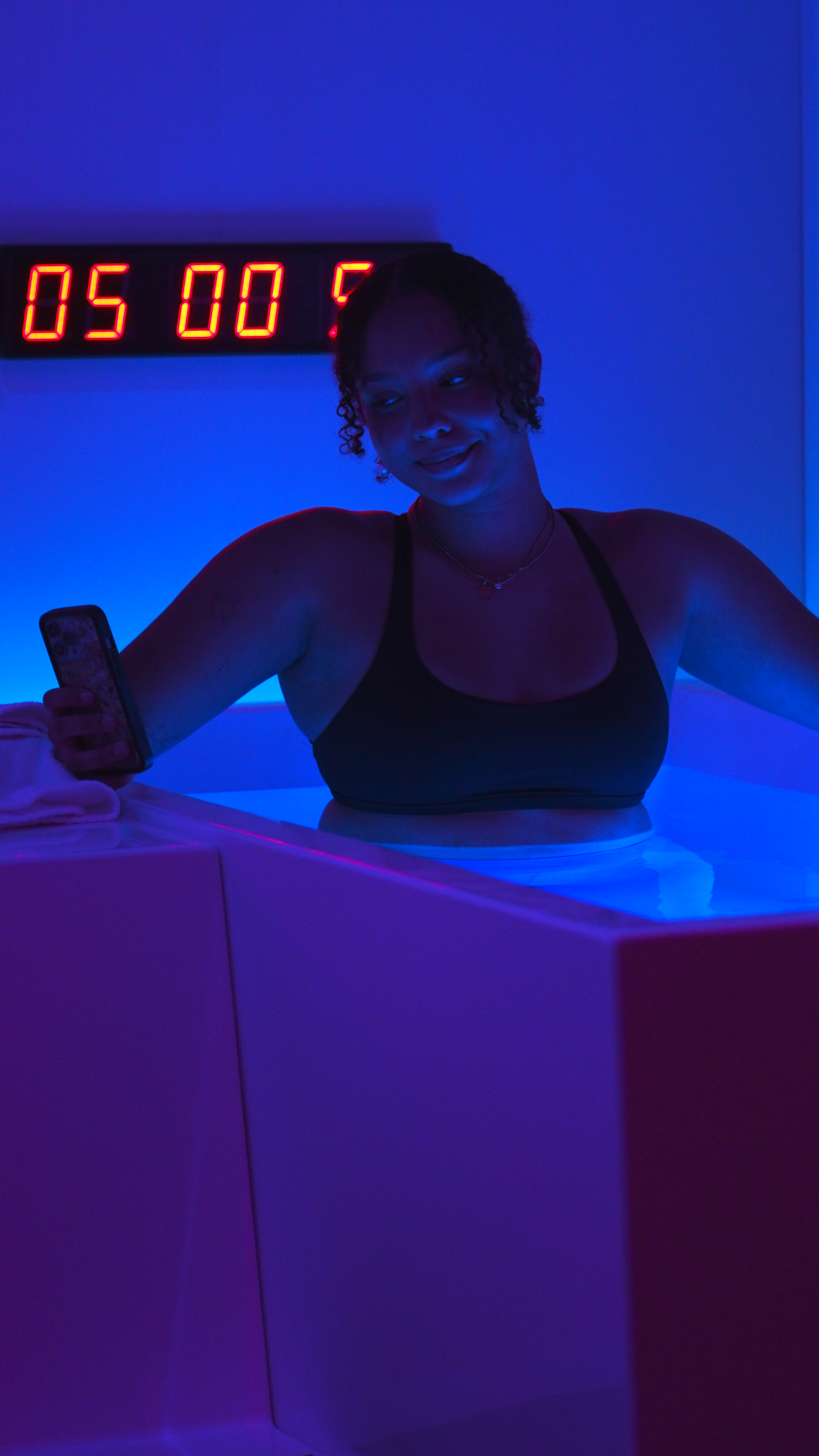 Woman standing by cold plunge tub with digital timer display
