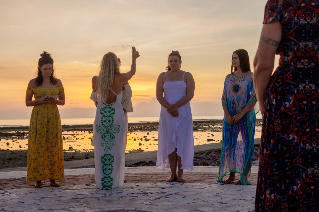Women's circle holding hands at sunset