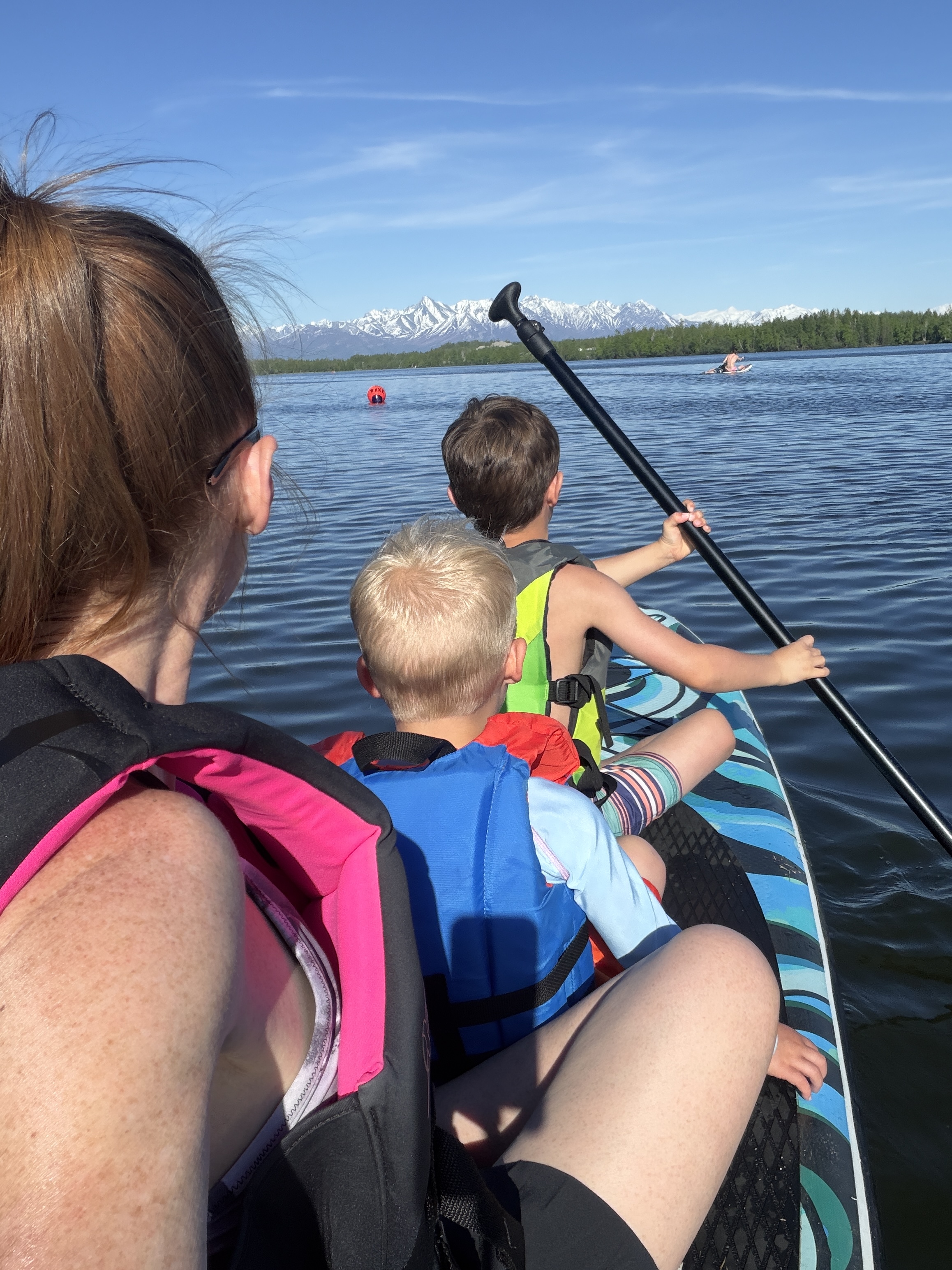 Paddleboarding with her two boys, mountains in the background