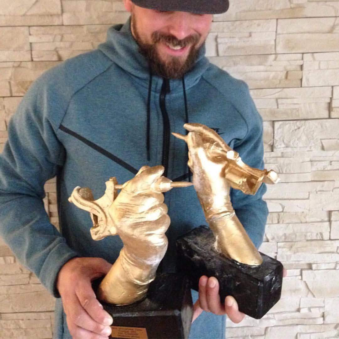 Torsten Malm holding two golden-hand tattoo convention trophies