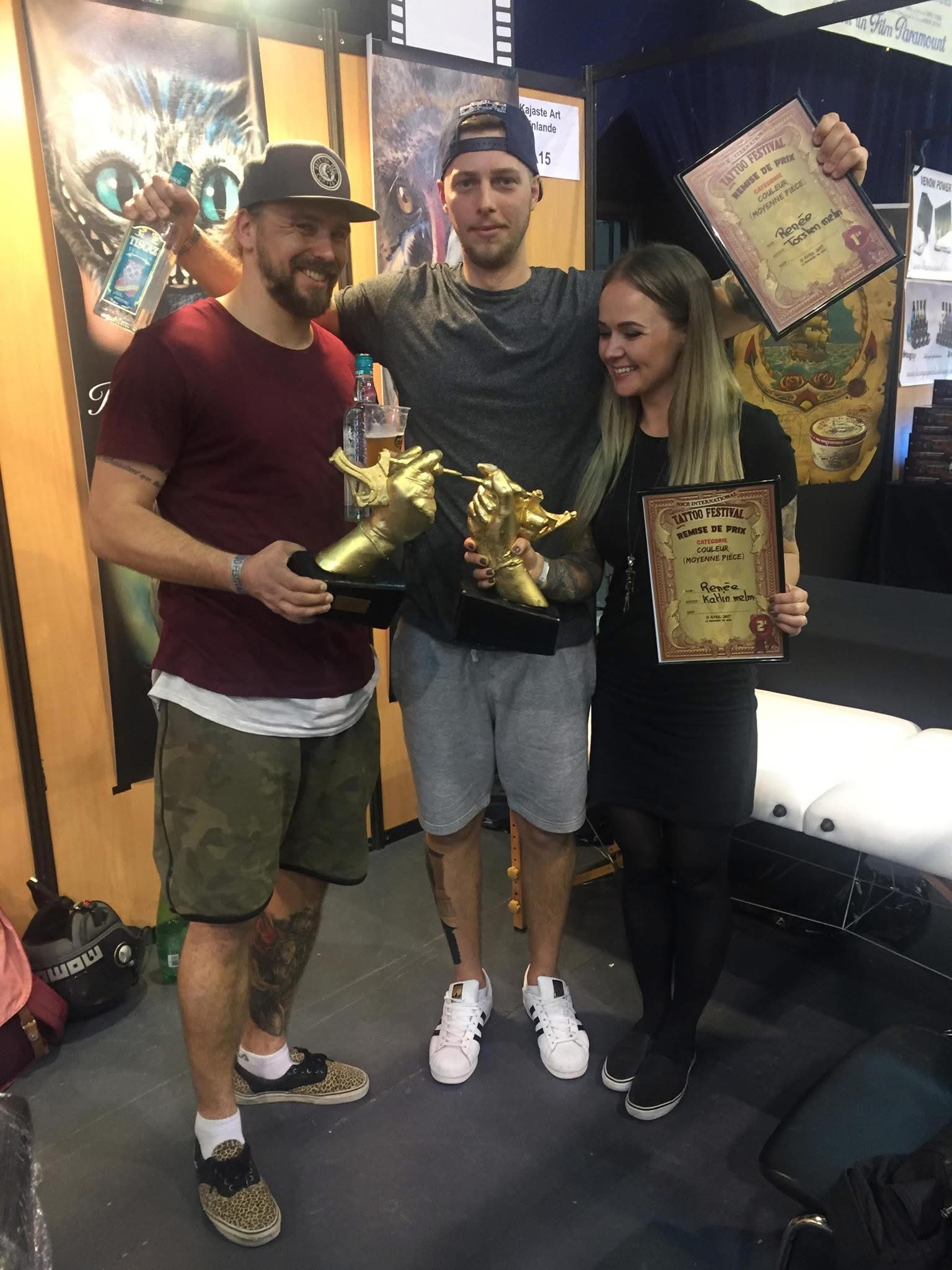 Torsten Malm holding Nice International Tattoo Festival certificates and a golden-hand trophy