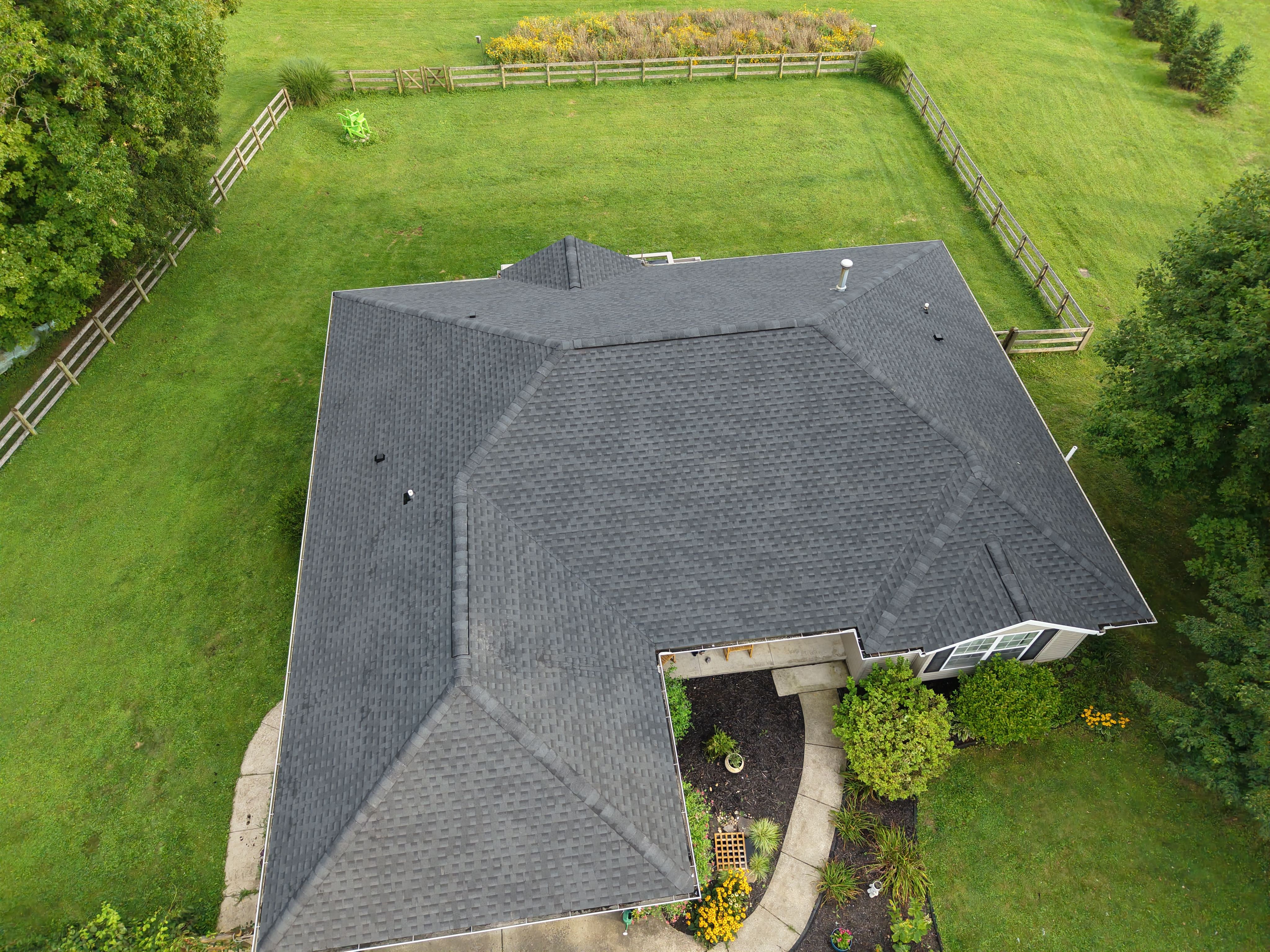 An aerial view of a large residential home featuring a completed asphalt shingle roof replacement by Weikles Roofing, with a Traeger Ironwood 885 smoker with a red bow placed in the driveway as a promotional giveaway incentive. - Weikles Roofing An aerial view of a large residential home featuring a completed asphalt shingle roof replacement by Weikles Roofing, with a Traeger Ironwood 885 smoker with a red bow placed in the driveway as a promotional giveaway incentive. - Weikles Roofing