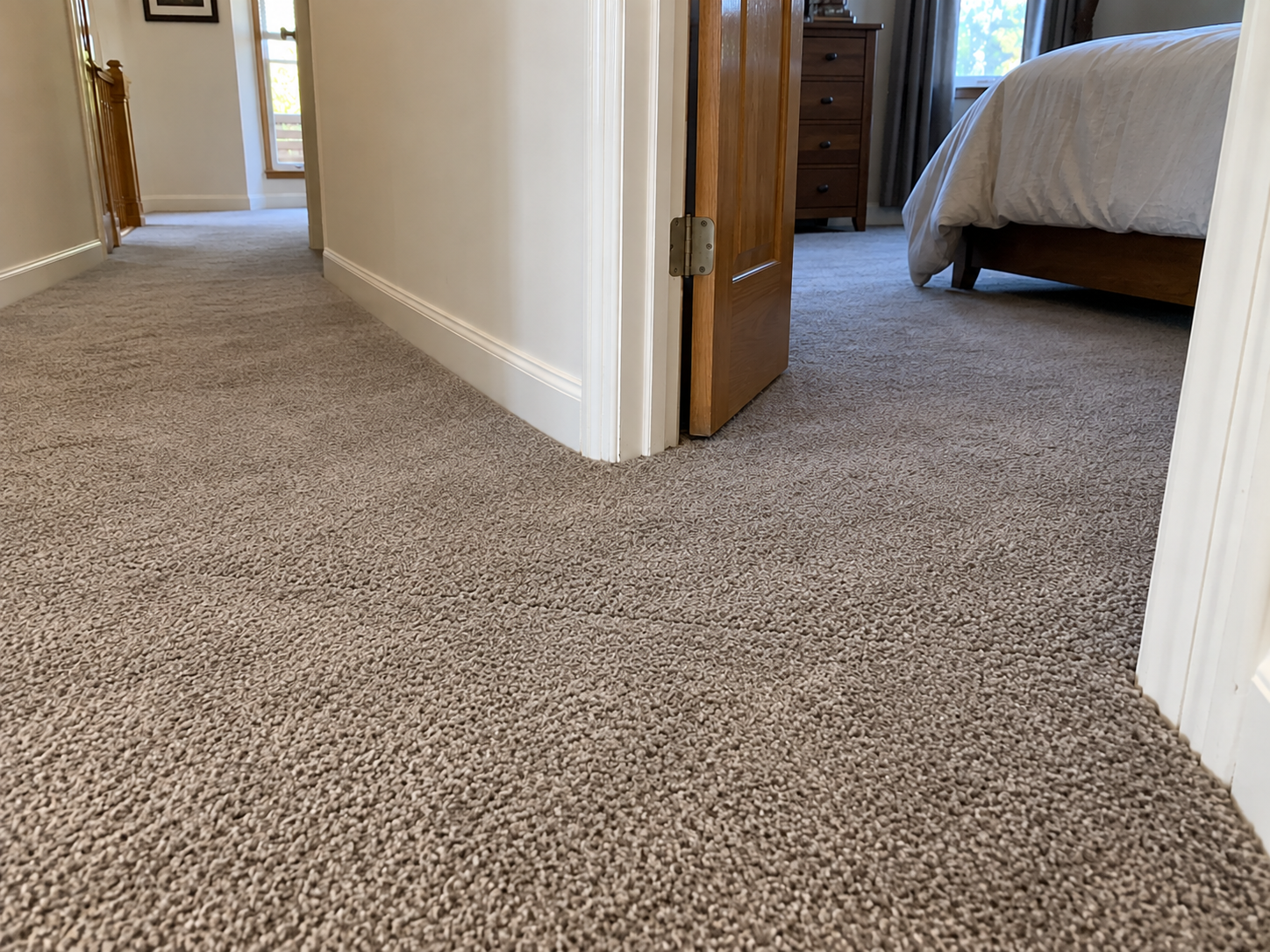 After: the same doorway seam re-joined and invisible in the taupe carpet