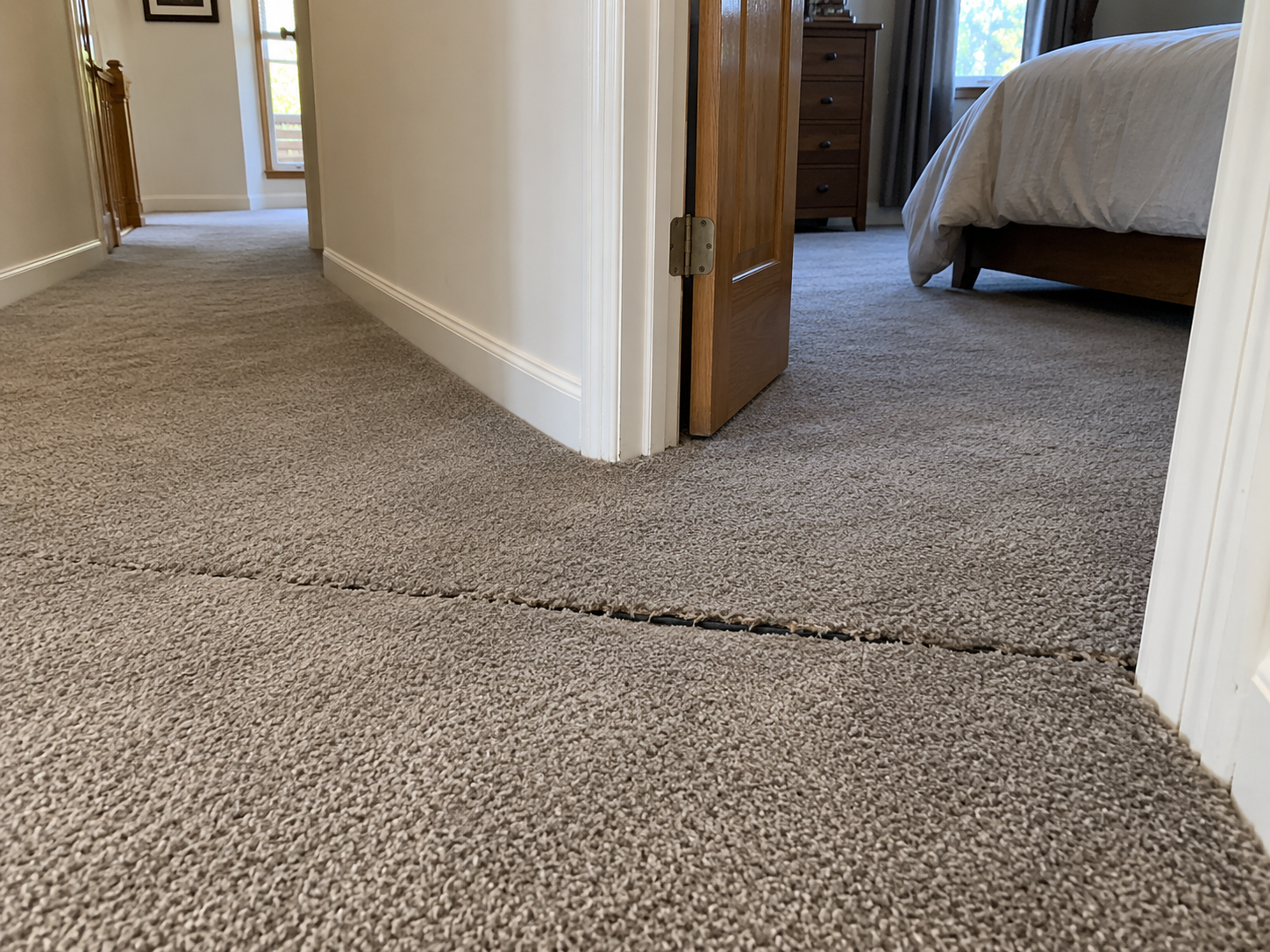 Before: split carpet seam at a bedroom doorway with a visible gap exposing the seam tape