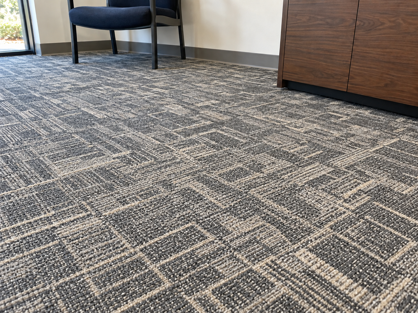 After: the same office carpet with the dark stain removed and the tile pattern clean again