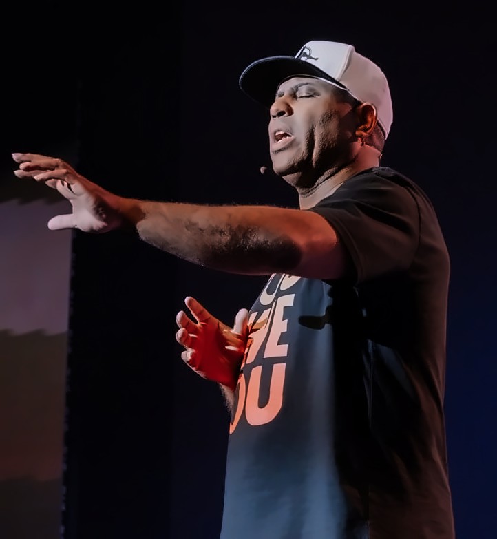 ET speaking with his hands out on stage
